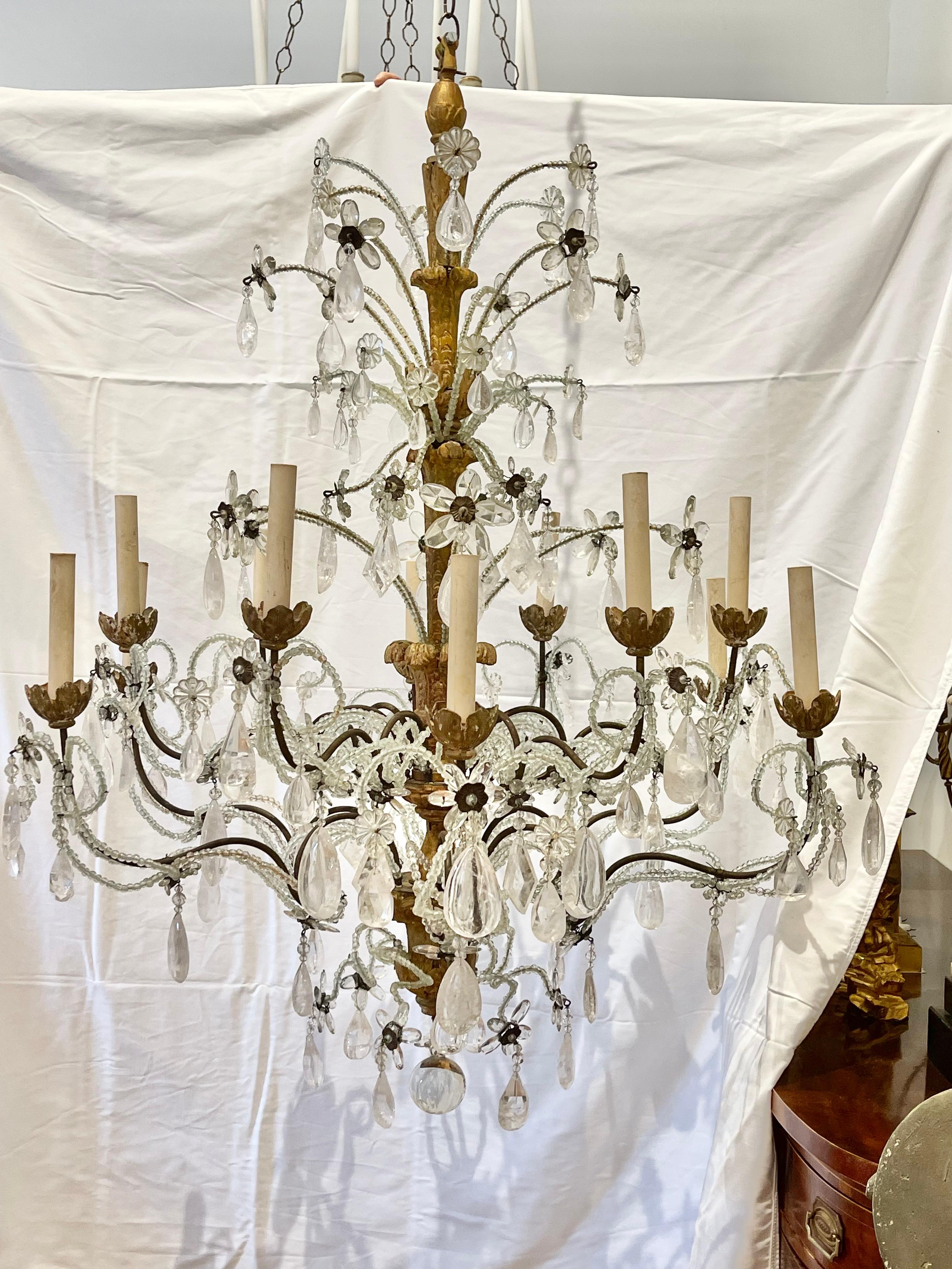 A north Italian giltwood, gilt-metal, cut-glass and rock crystal twelve-light chandelier
Genoa, 18th century
The central foliate-carved baluster shaft issuing sprays of beaded and faceted flowers and twelve scrolling candlearms lined with beads