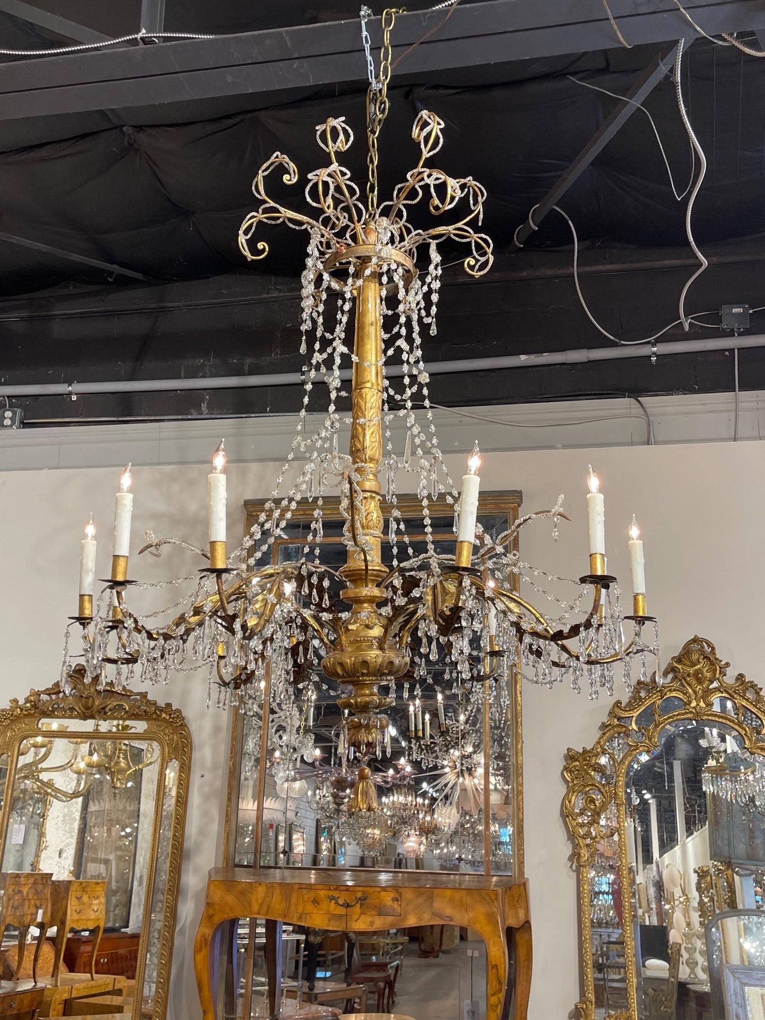 Very fine 18th century Italian large scale giltwood and beaded crystal chandelier with 18 lights. Beautiful carved base and pretty dangling crystals. Creates a nice light and airy feel. Impressive!