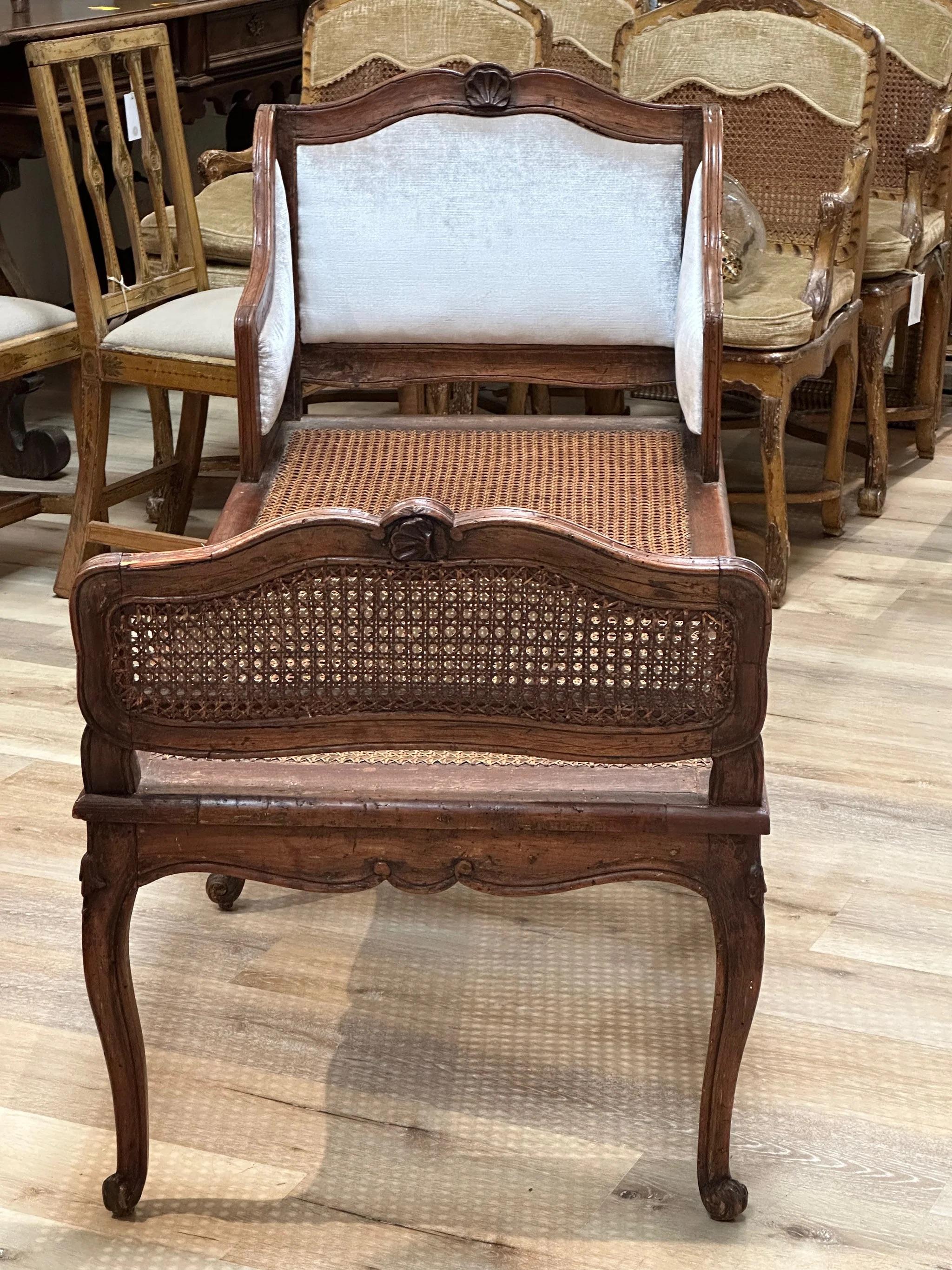 An exquisite 18th century Italian lit de repos or chaise lounge in walnut and cane. This spectacular chaise has a beautifully sculpted apron and cabriole legs. A particularly rich patina to this piece.  There is a large, comfortable cushion with the