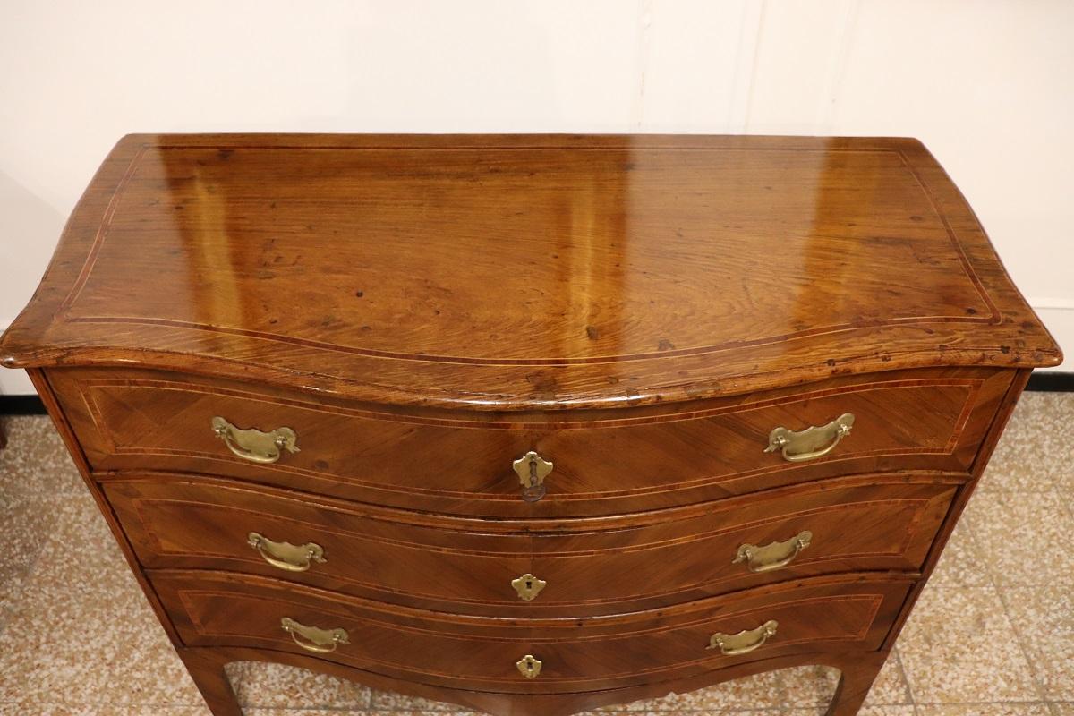 Nous vous présentons cette élégante commode italienne ancienne datant du milieu du XVIIIe siècle, période Louis XV. Une commode extrêmement raffinée, dont les caractéristiques suggèrent qu'elle a été fabriquée dans les ateliers d'ébénisterie du nord