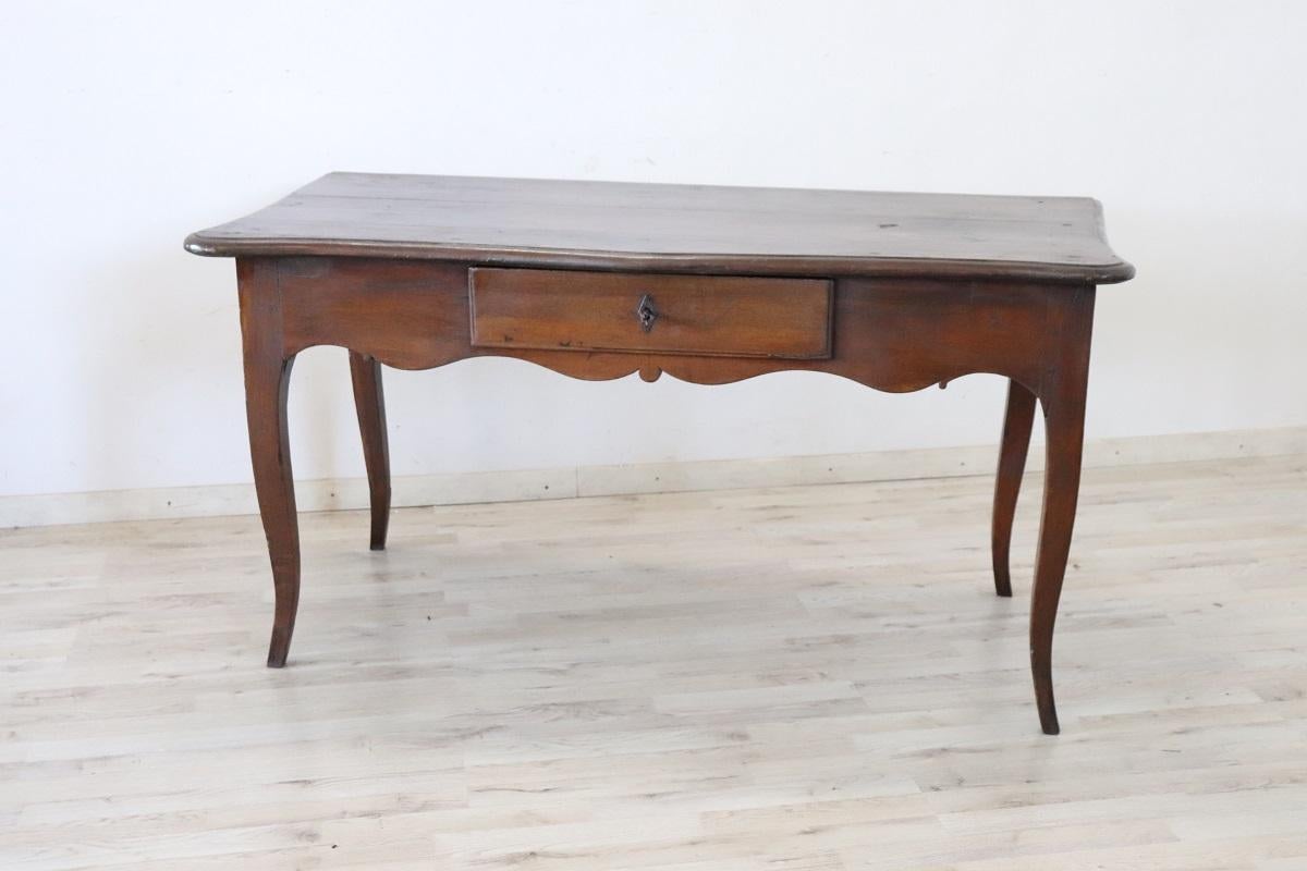 This Antique Italian Louis XV period desk table from the mid-18th century is an exquisite example of craftsmanship and design from this era. Constructed from solid oak wood, it epitomizes a rustic yet refined style. The desk features characteristic