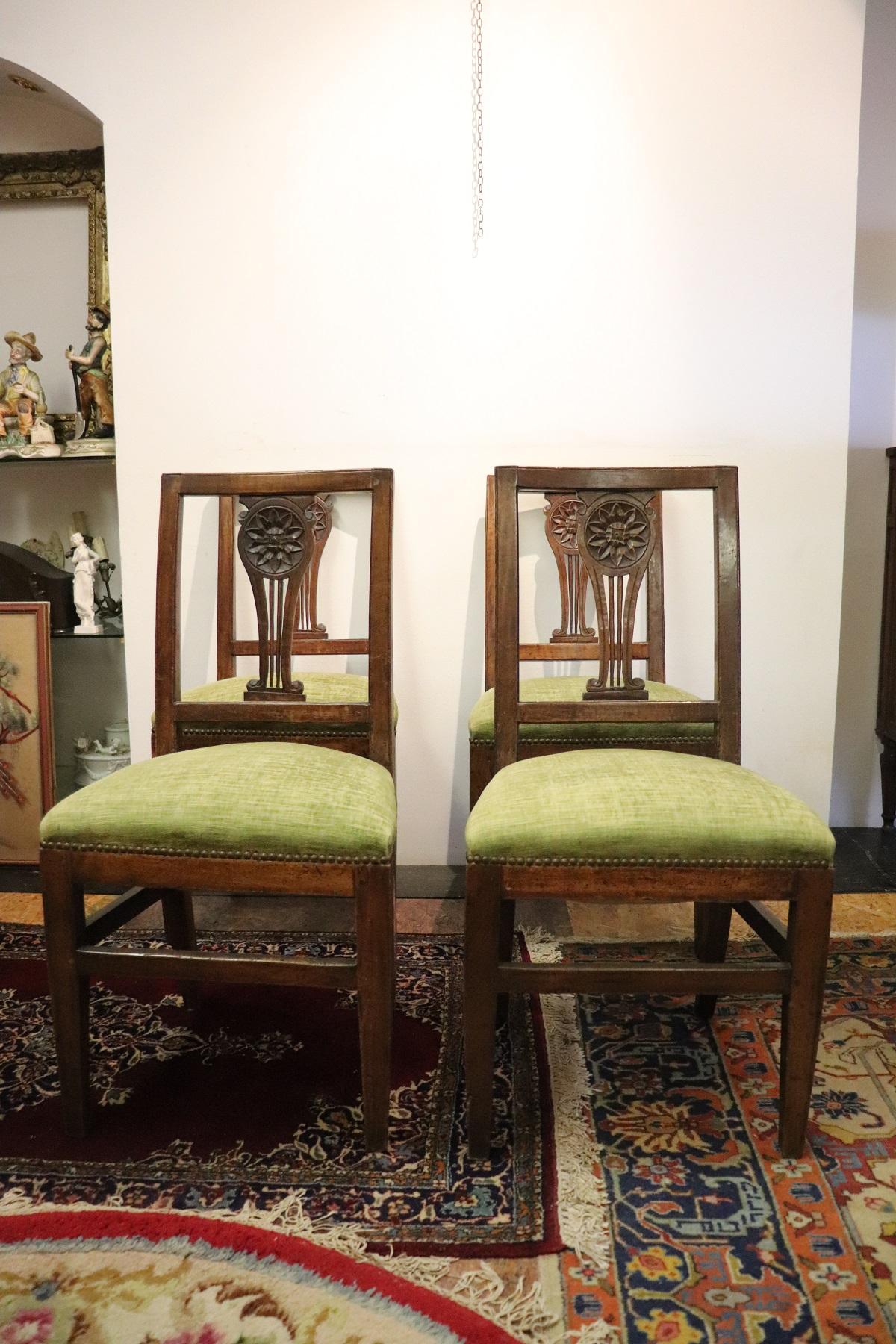 Series of four refined 18th century authentic Italian Louis XVI walnut wood four chairs. Refined decoration the back is carved with a large flower. The legs are very elegant straight. The seat is wide and comfortable. Cloth light green color used