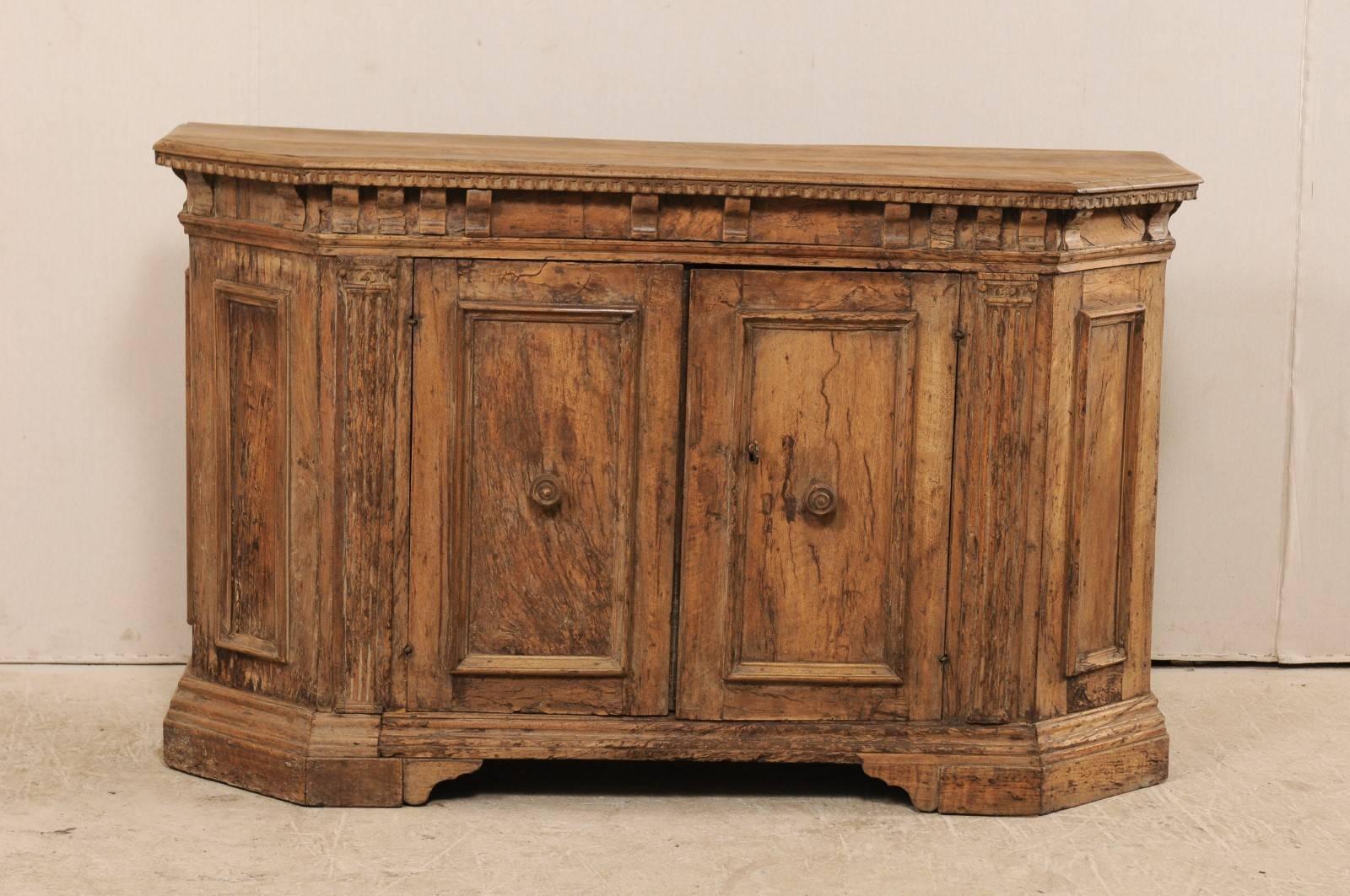 An 18th century Italian sideboard console cabinet of walnut wood. This antique French sideboard of beautiful walnut wood is decorated with rectangular-shaped recessed panels, canted side posts, a slightly overhanging ornately trimmed, and is raised
