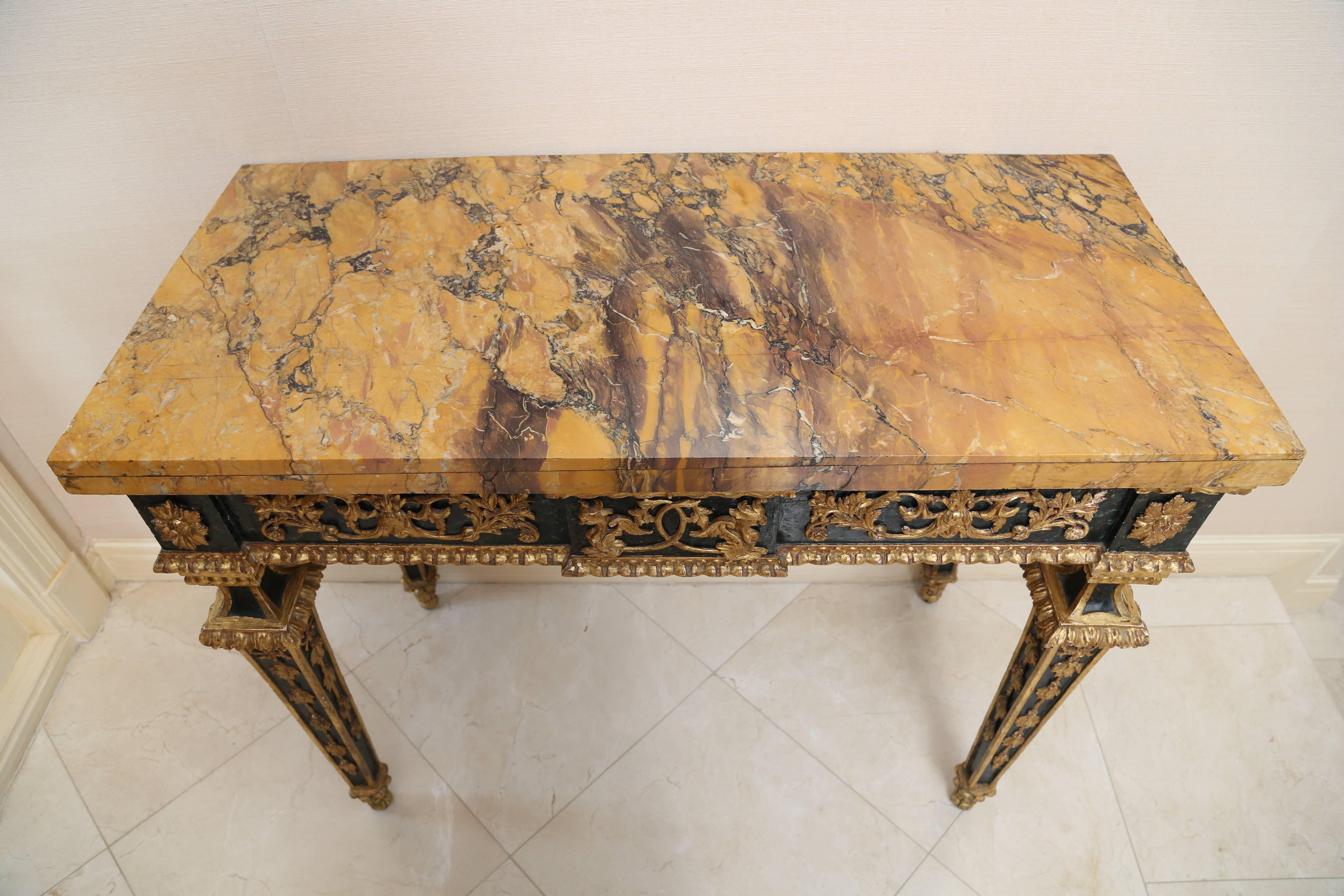 The later rectangular marble-top over a green faux marbre frieze with low relief gilt decoration of griffins and foliate scrollwork; raised on square tapering legs headed by sunburst medallions and enriched with ribbon-tied husk garlands,
