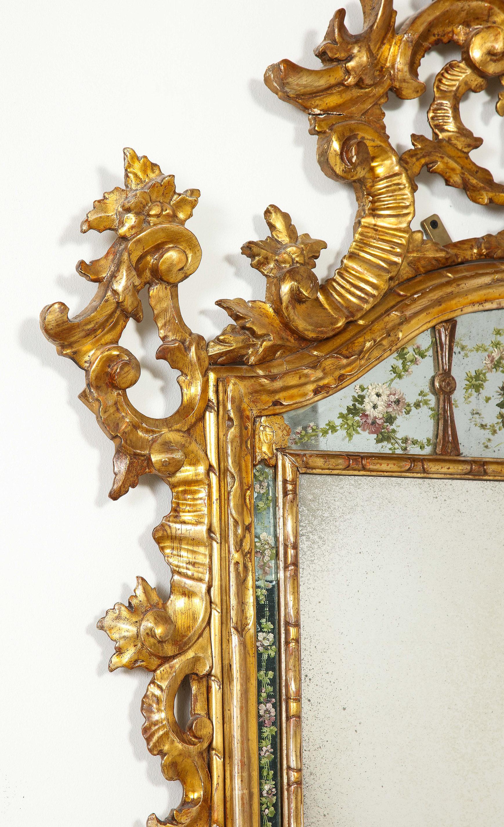 Ein seltener und eleganter venezianischer Spiegel aus vergoldetem Holz aus dem 18. Mit fein gemalten Flora auf allen, aber die wichtigsten Spiegelplatte, Laub und Girlande Schnitzerei im gesamten Rahmen.