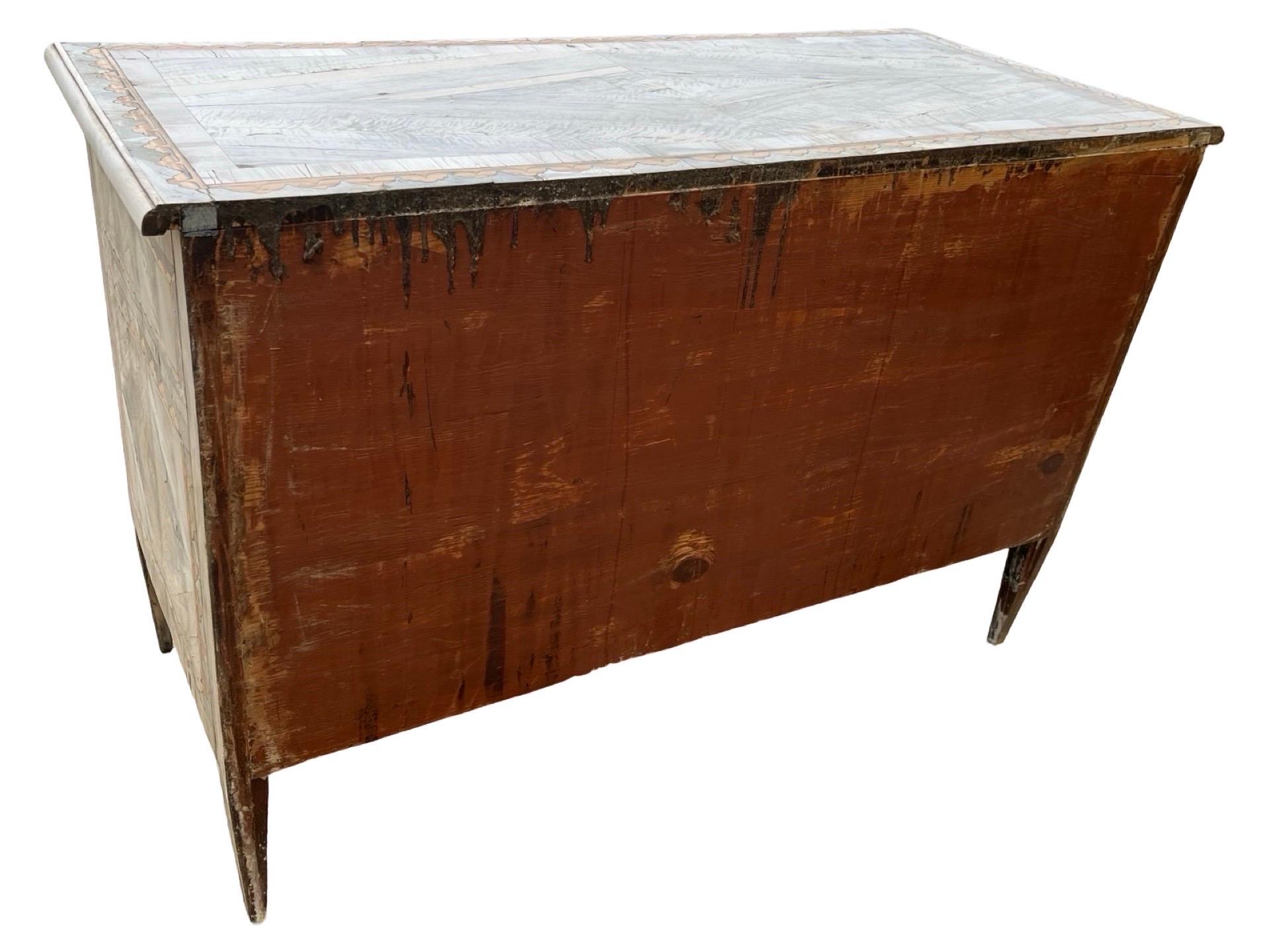 Neoclassical commode hand-made in Italy in the late 1700s using pine and decorated with walnut veneer with satinwood inlay. The chest of drawers features extremely straight lines and sits on long, tapered feet. Three inset drawers can be seen on