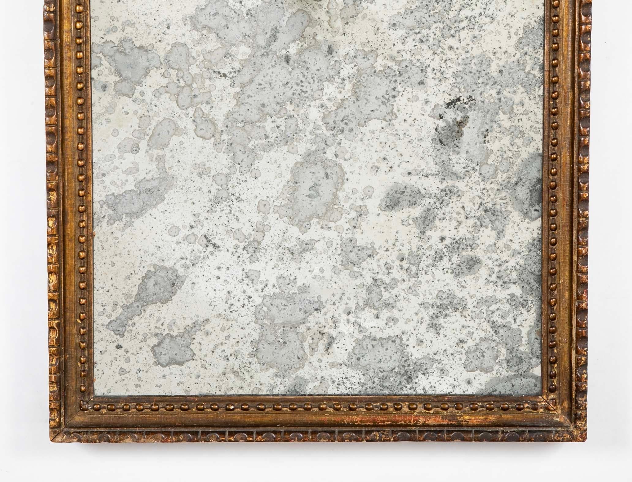 Cornice neoclassica italiana del XVIII secolo in legno dorato con vetro anticato. La cornice intagliata con decorazione a perline sulla modanatura interna e gadrooning su quella esterna. Meravigliosa patina superficiale che si ottiene solo con l'età