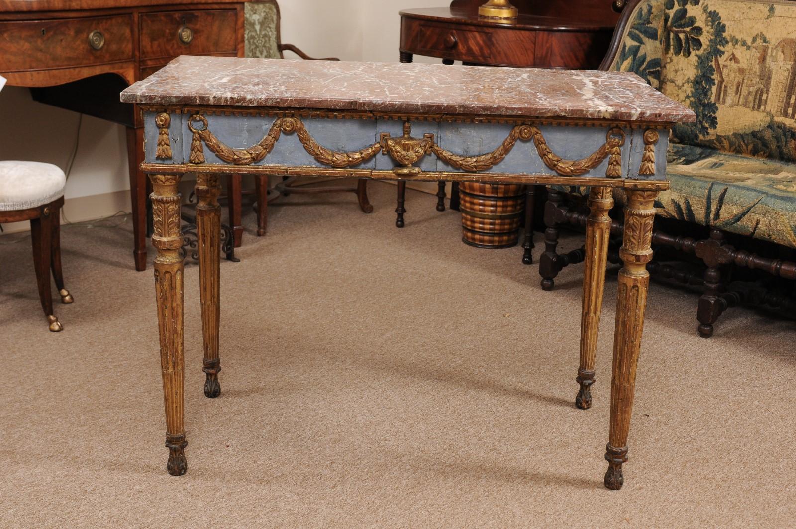 The Italian neoclassical center or console table with rouge marble top, finished on all sides with swag and urn gilt carving on frieze with pale blue painted ground. All resting on gilded fluted carved legs and rounded feet. 

 