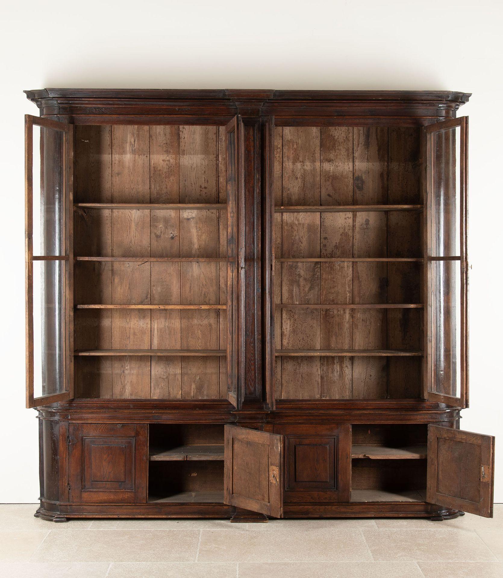 Grande vitrine italienne du XVIIIe siècle à quatre travées, aux angles arrondis, la base comportant des armoires naines. La corniche en saillie surplombe quatre portes vitrées contenant le vitrage d'origine et ayant des cadres moulés élaborés