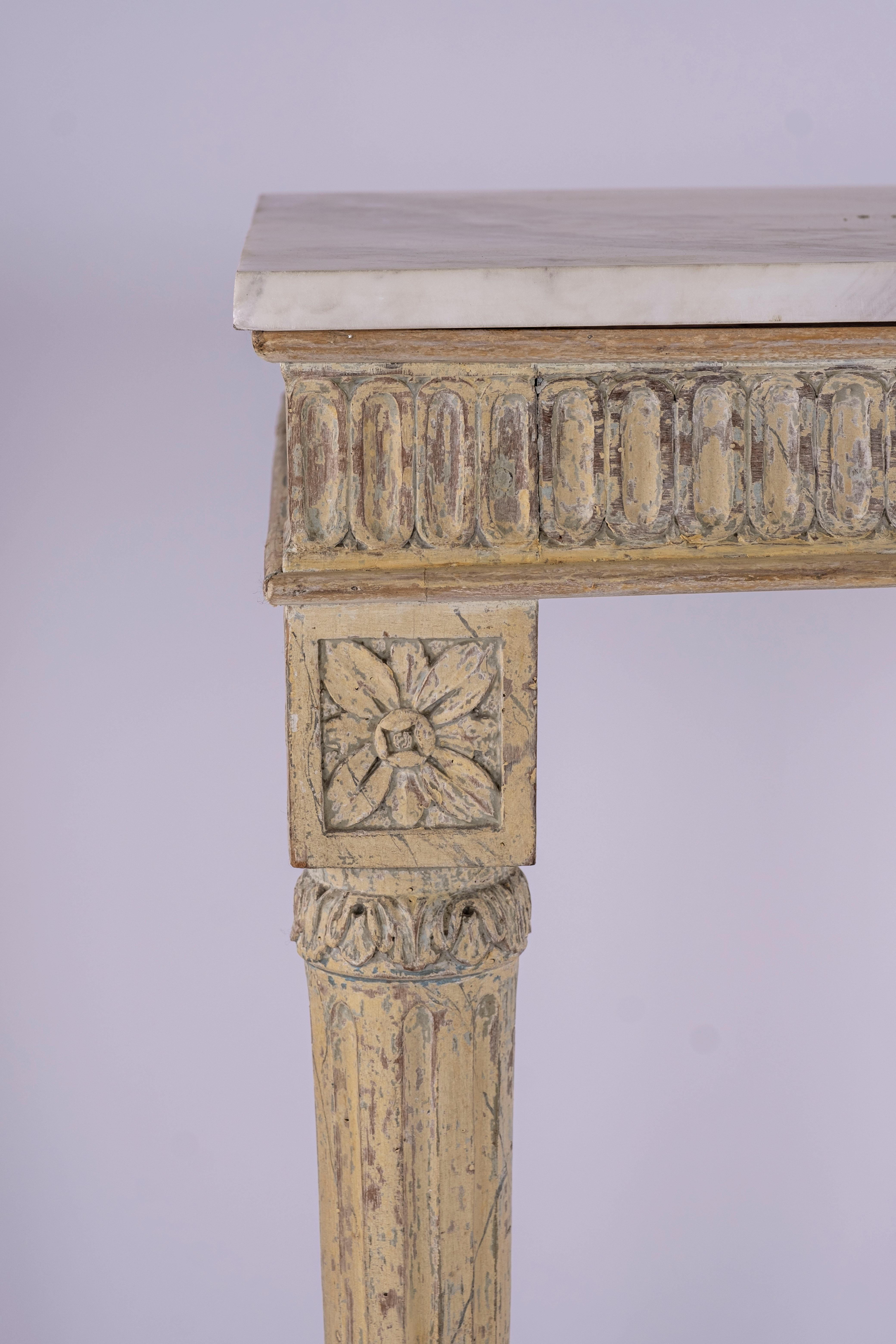 18th century Italian console table with original paint. The top supports a later addition of white marble. Carved fluted frieze and flower carved blocks above four tapered and fluted legs.