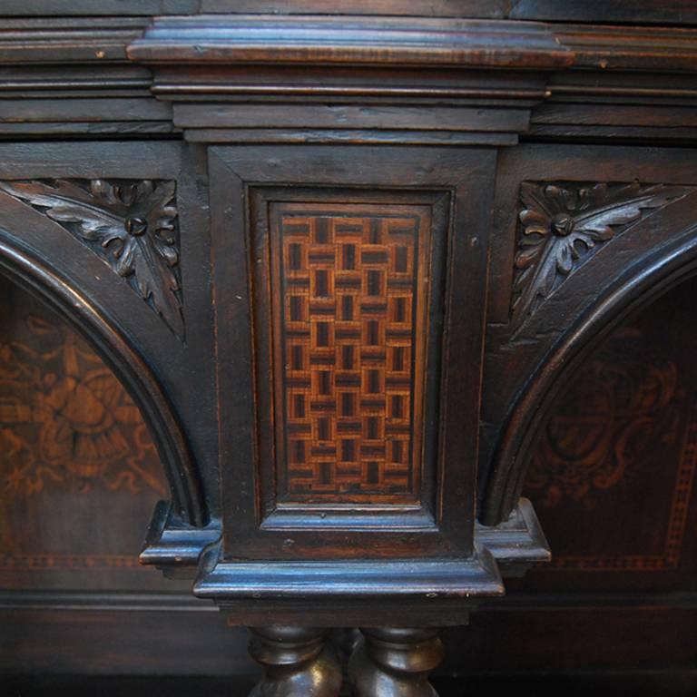 An incredible 18th century Italian cabinet with beautiful parquetry inlaid door panels depicting architectural ruins and classical figures. The body of the cabinet features wonderfully carved figures, cherubs, and barley twist columns supporting the