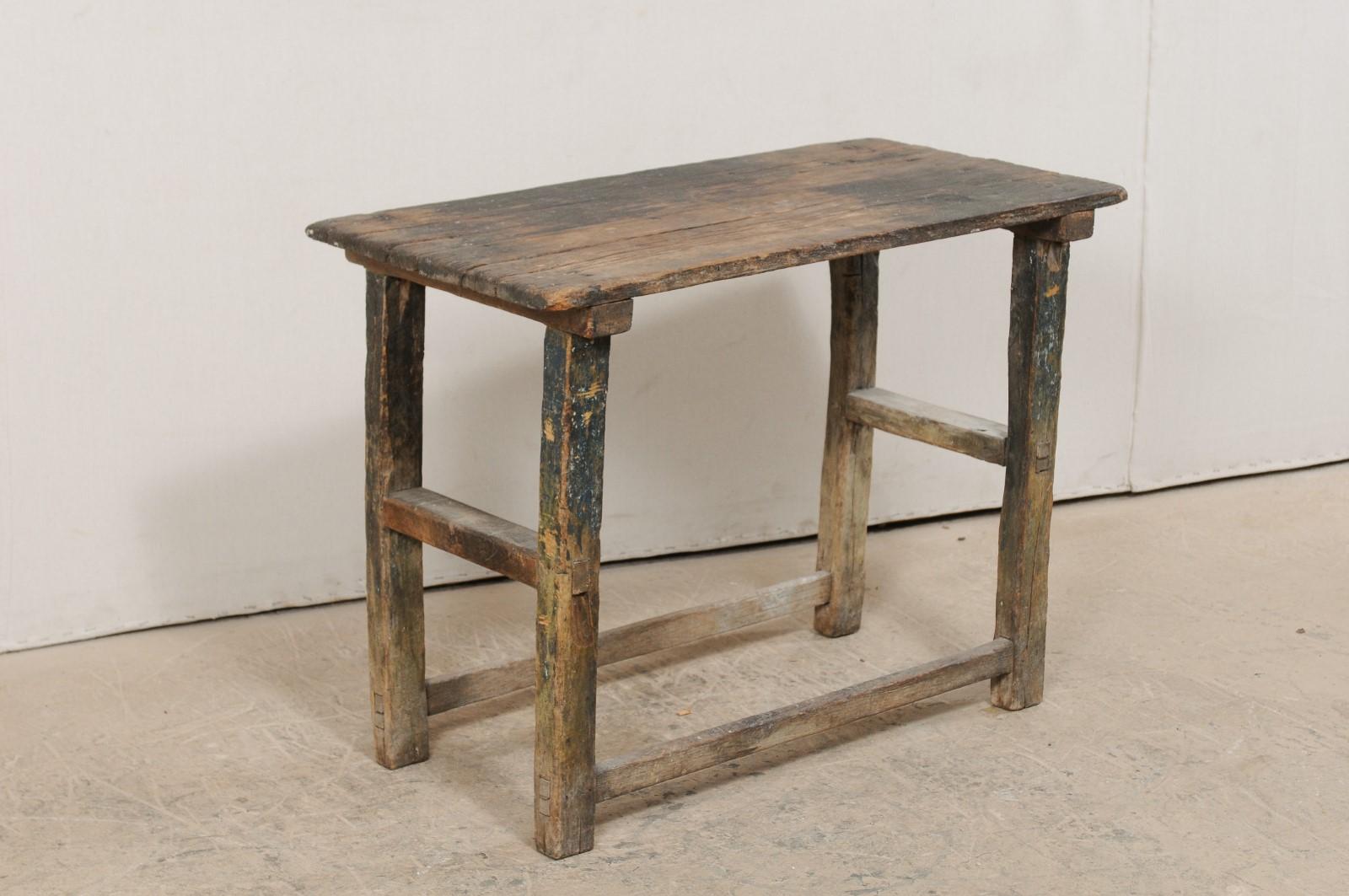 An Italian Primitive wooden occasional table from the 18th century. This smaller-sized antique table from Italy features a rectangular-shaped top, which is raised on four squared legs with stretchers between. This piece has a wonderful old patina