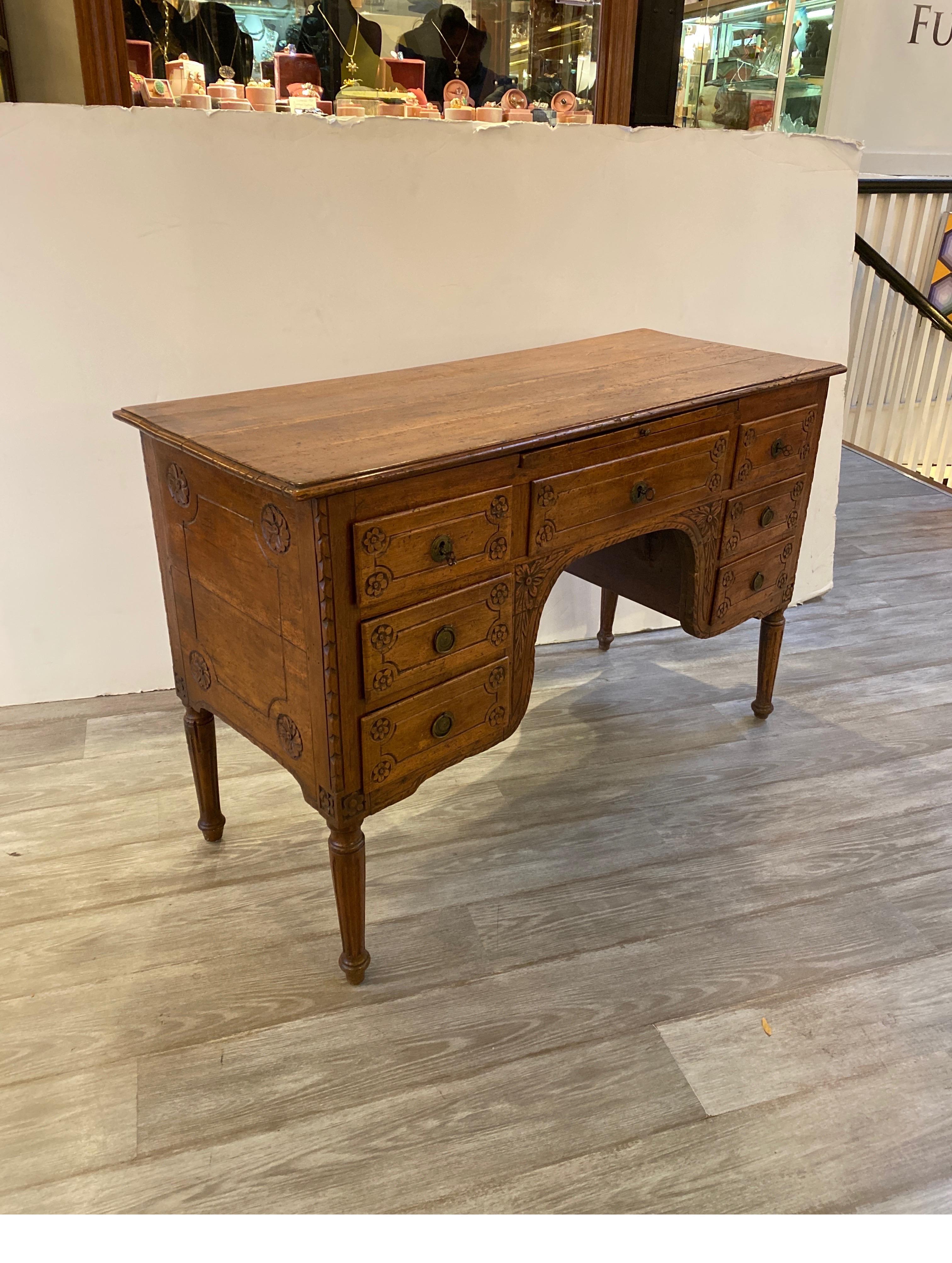 A hand carved walnut or fruitwood Italian desk. The desk with a center drawer with three side drawers on each side. Above the central drawer is a pull out tray for drafting and additional work space. The desk in in beautiful aged condition with
