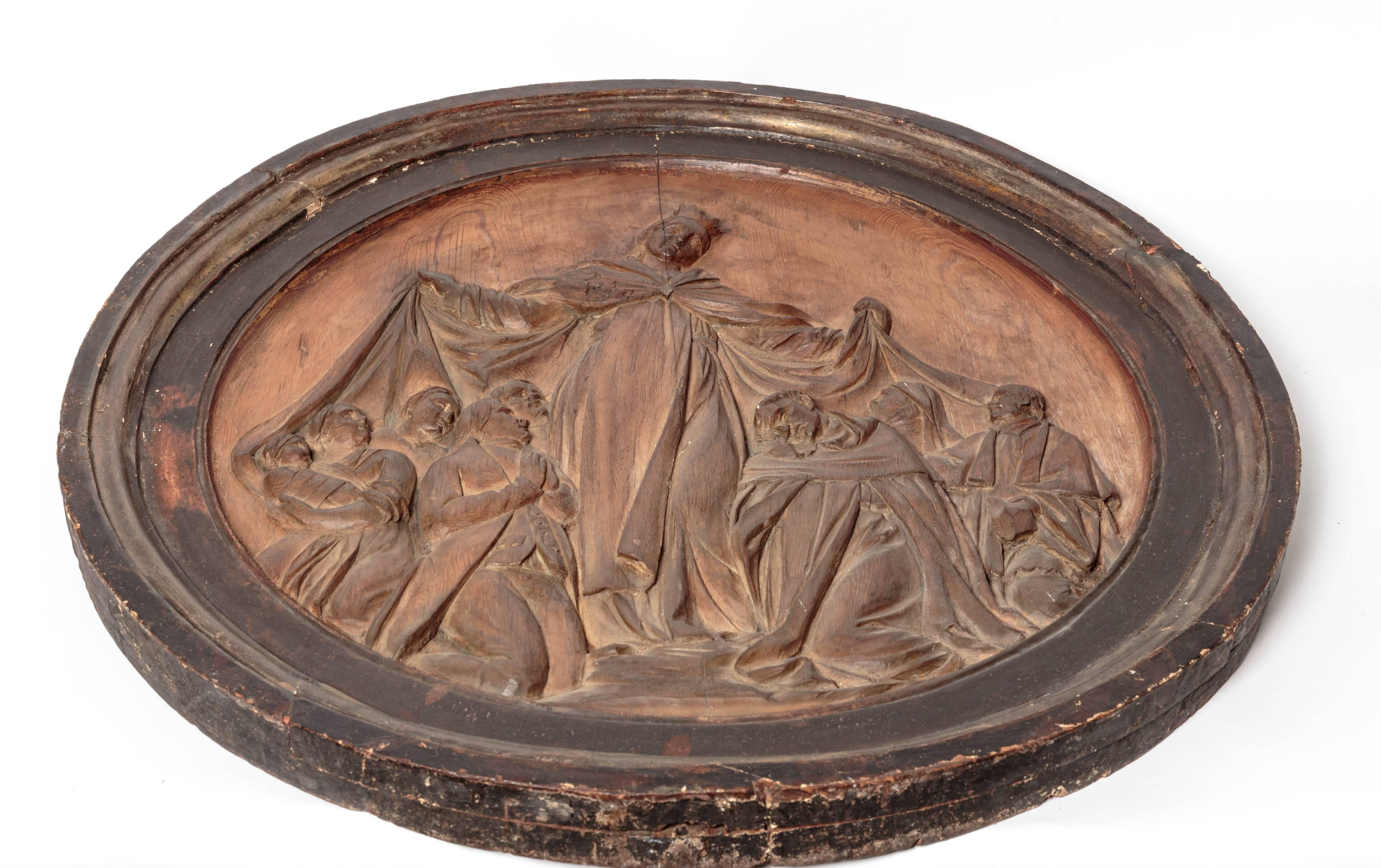 Beautiful hand-carved religious artifact depicting Virgin Mary surrounded by church and state. Base relief form finishing in round frame. Stunning piece.