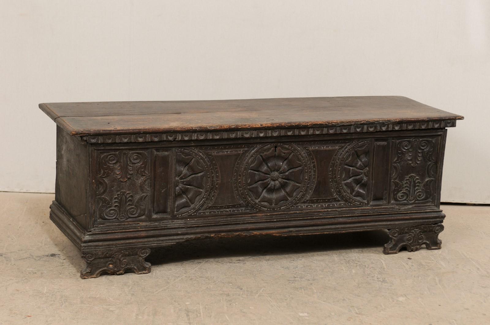 An Italian 18th century nicely carved wooden trunk on raised feet. This antique cassone, or wedding chest, from Italy features an exquisitely hand carved front panel adorn with a center medallion flanked within a pair of halved medallions, and