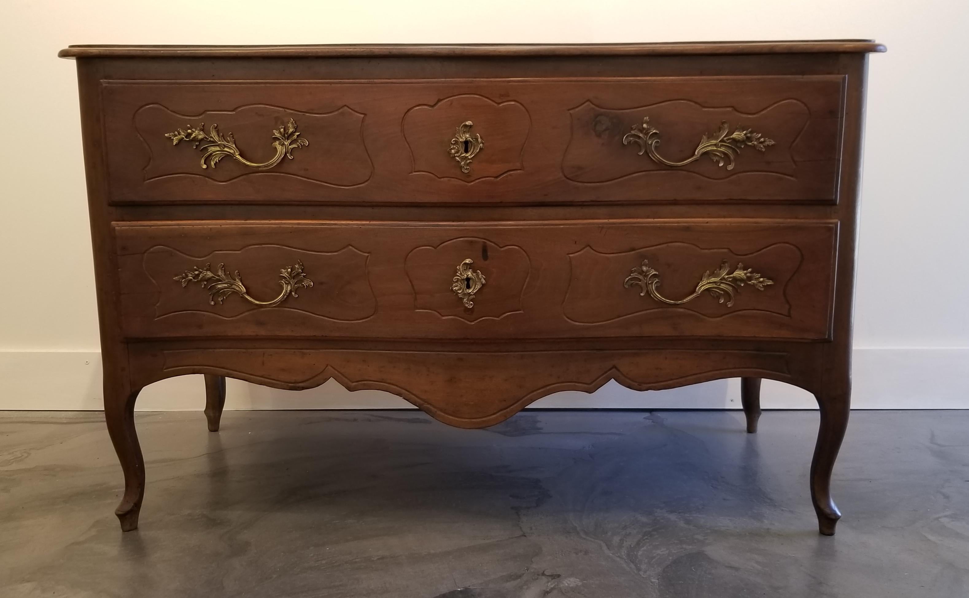 A mid-18th century Italian 2-drawer walnut commode with olive secondary woods. Retains original hardware, escutcheon plates and locks. Serpentine front on cabriole legs with hoof feet, circa 1760.