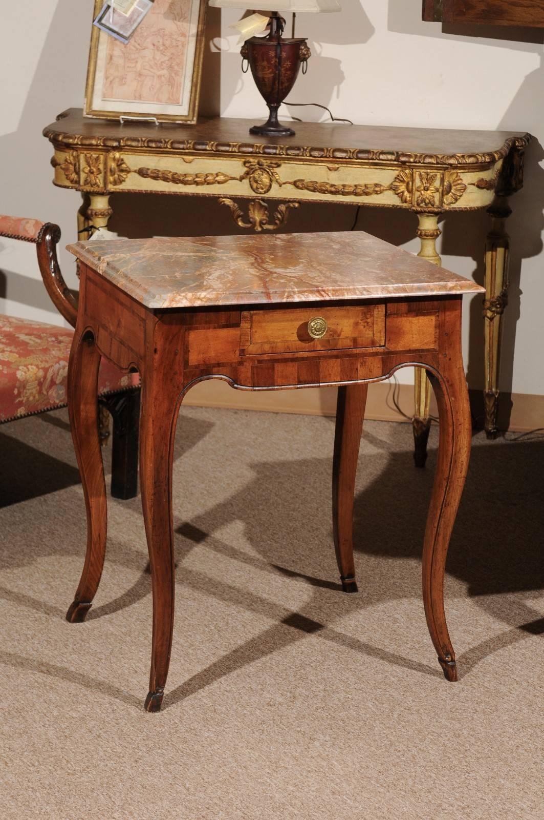 The Rococo walnut inlaid table with marble top in grey and salmon hues resting on walnut base in Rococo form with drawer, cabriole legs and hoofed feet. 


 