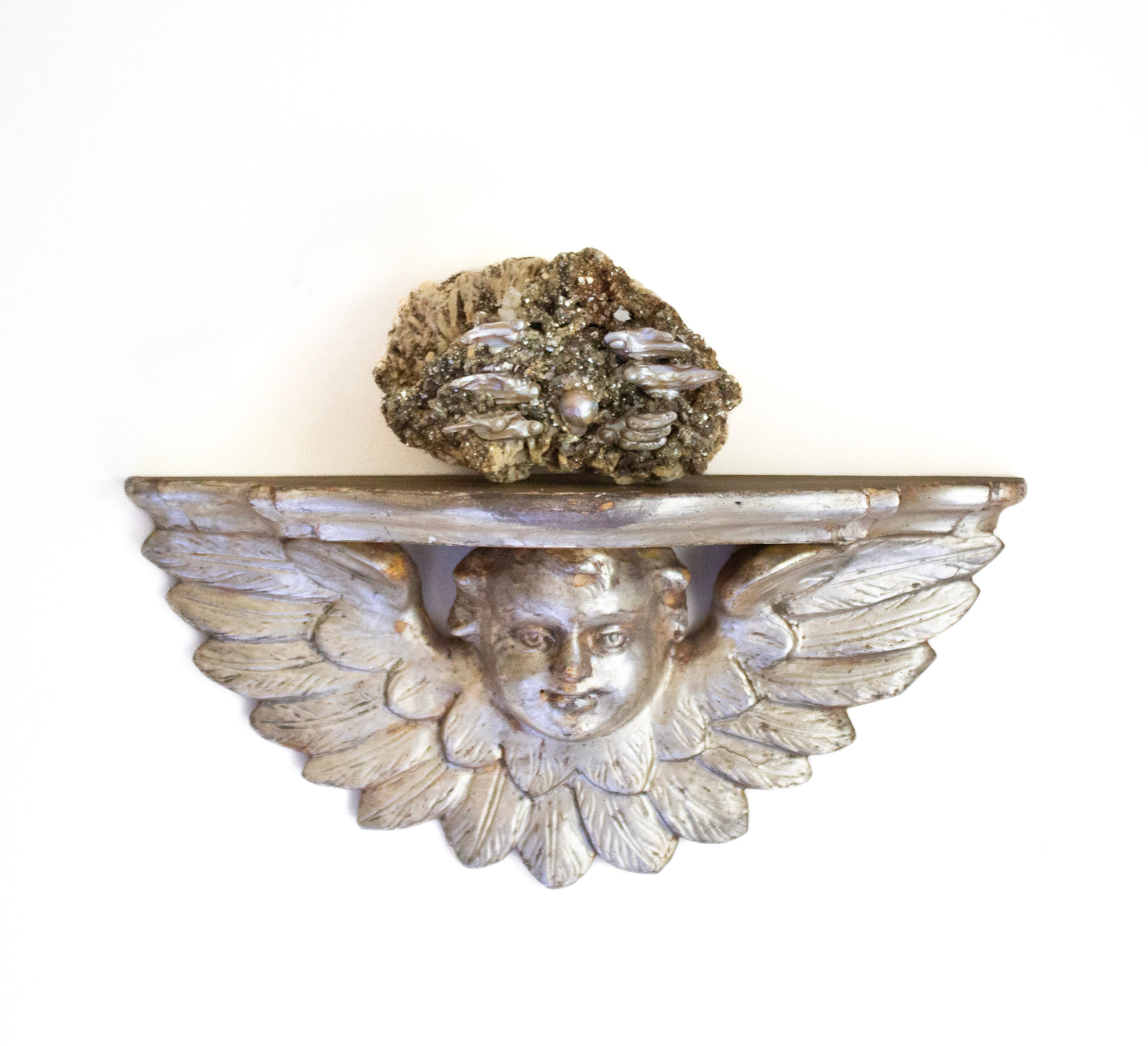 Ménsula de ángel de plata italiana del siglo XVIII montada con mica y pirita en matriz y perlas barrocas.

El artefacto del ángel procede de una iglesia o palacio histórico de Italia. Está montada con la rara mica y pirita en formación de matriz y