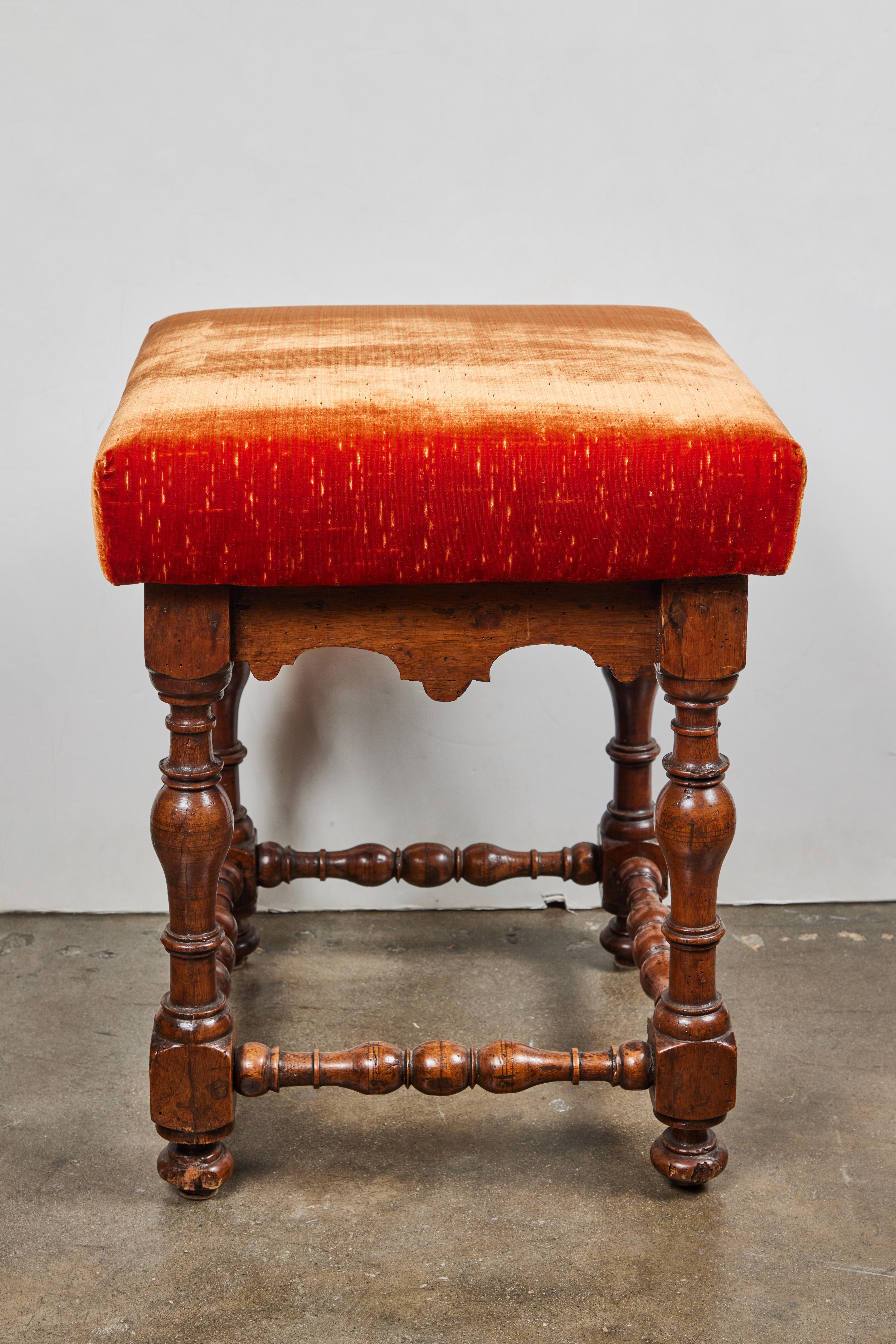 A fine pair of hand-carved, solid walnut, 18th century Tuscan stools. Each with serpentine aprons and standing on turned legs and stretchers. Covered in luxurious, burnt sienna, Scalamandre silk velvet.