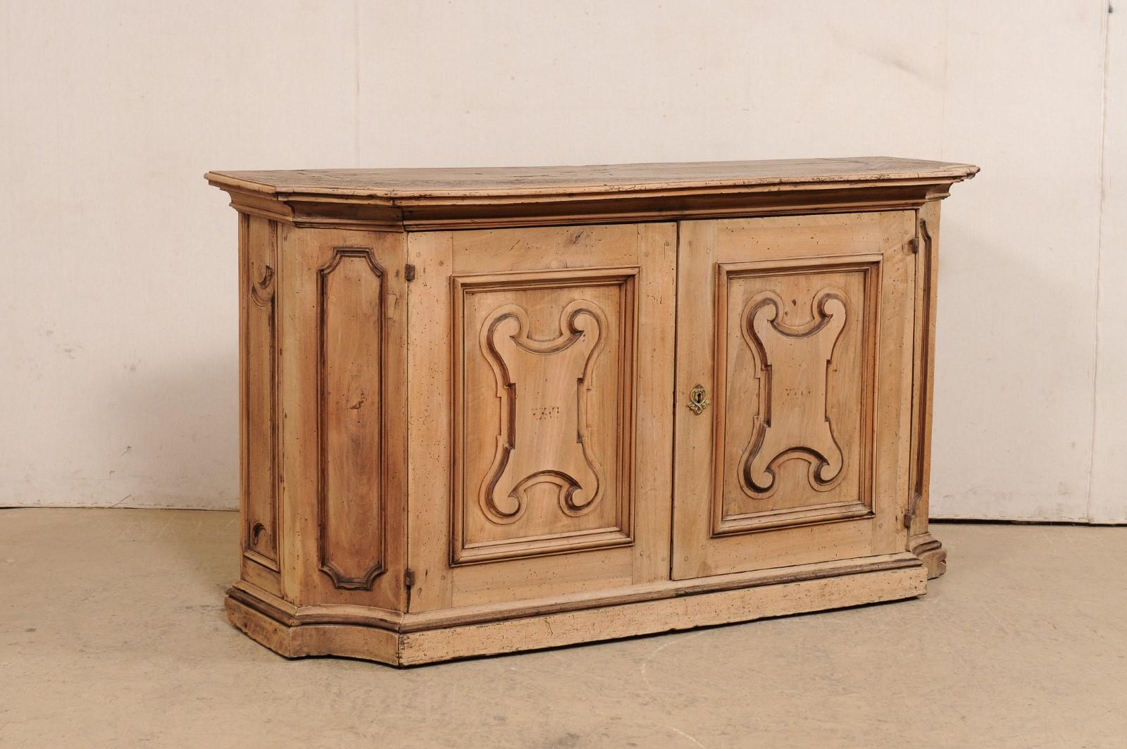An Italian carved-wood console chest from the 18th century. This antique cabinet from Italy has a breakfront style design, with convex side posts flanking the pair of doors housed at center, and presented upon a platform style base. Decoratively