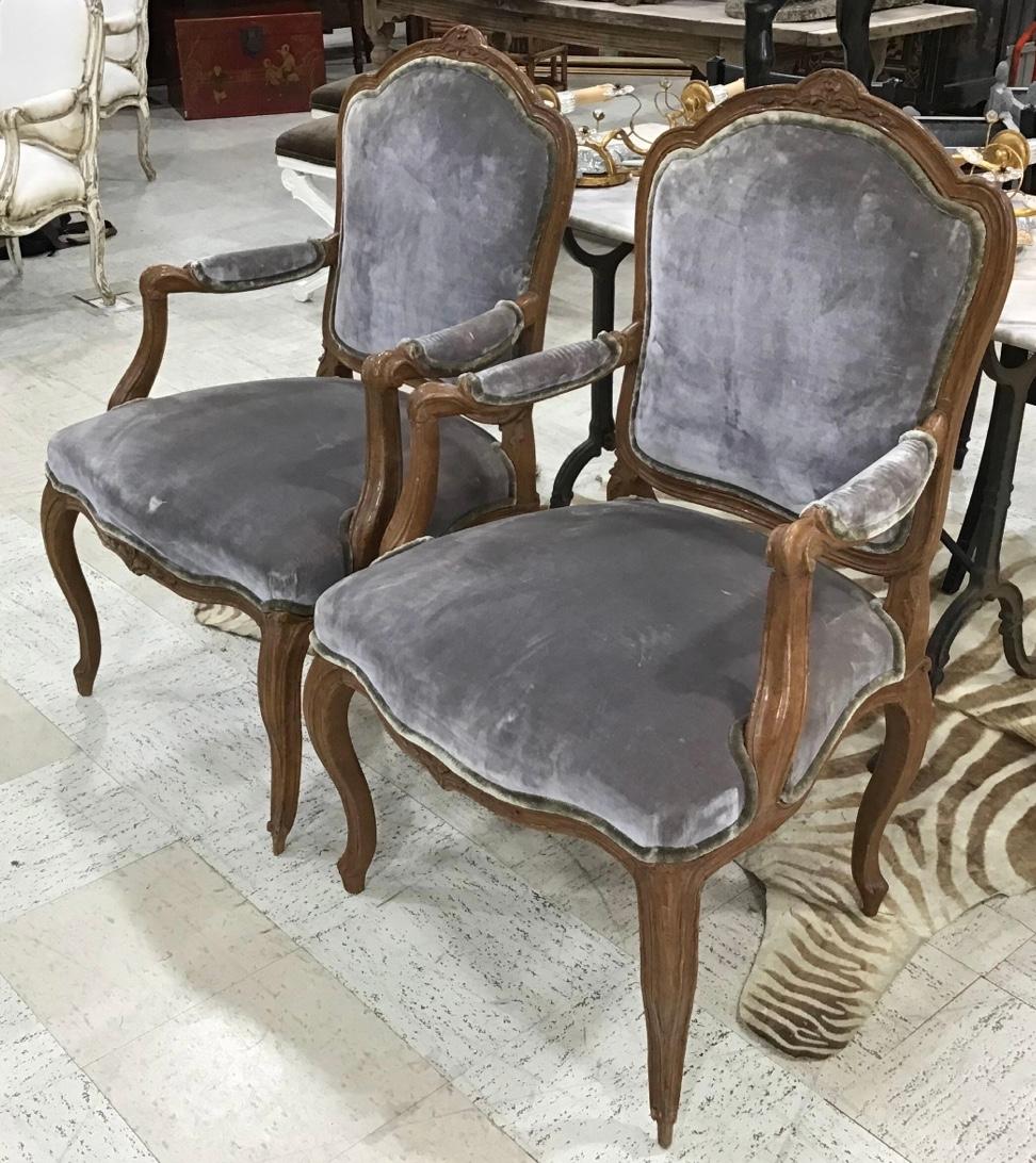 Handsome and impressive pair of Italian 18th century Louis XV carved walnut armchairs. The four cabriole legs below scrolled arms and curved and large back with a moulded design and a top central floral carving. Wonderful exaggerated scale and warm