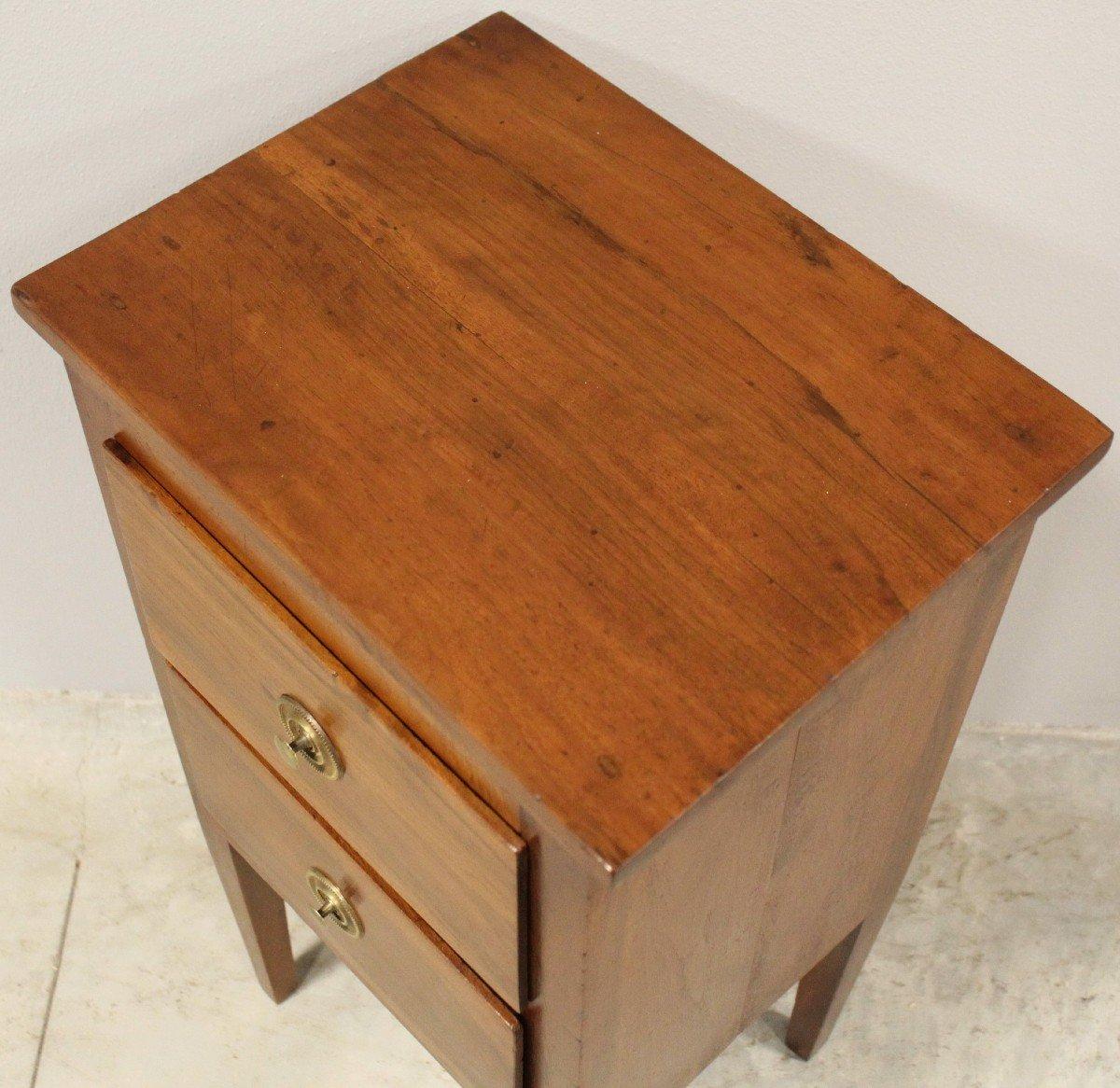 An Italian walnut bedside table from the 18th century with two drawers, tapered legs and brass hardware. Immerse yourself in the luxury of 18th-century Italian design with this walnut bedside table. Crafted from rich, warm walnut wood, this stunning