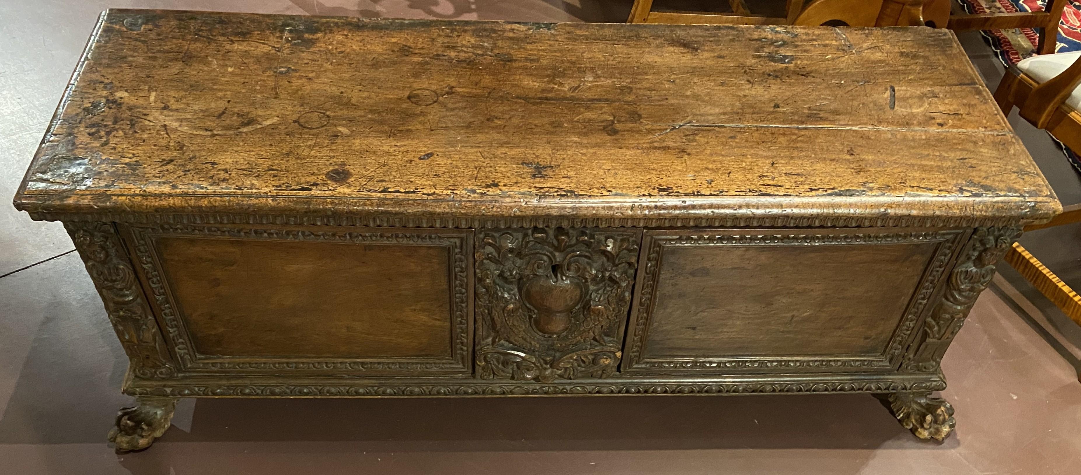 Un bell'esempio di cassone italiano in noce con un intaglio centrale a volute affiancato da un intaglio a figure su ciascuna estremità, un intaglio decorativo a bordi geometrici sul coperchio e che continua sui pannelli della cassa e sulla base, e