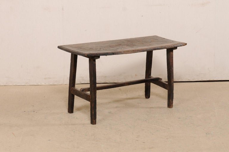 An Italian walnut wood coffee table from the 18th century. This antique table from Italy has a rectangular-shaped top, which is raised on a pair of saw-horse style legs at either far end, and braced with an H-shaped wood stretcher. This walnut piece