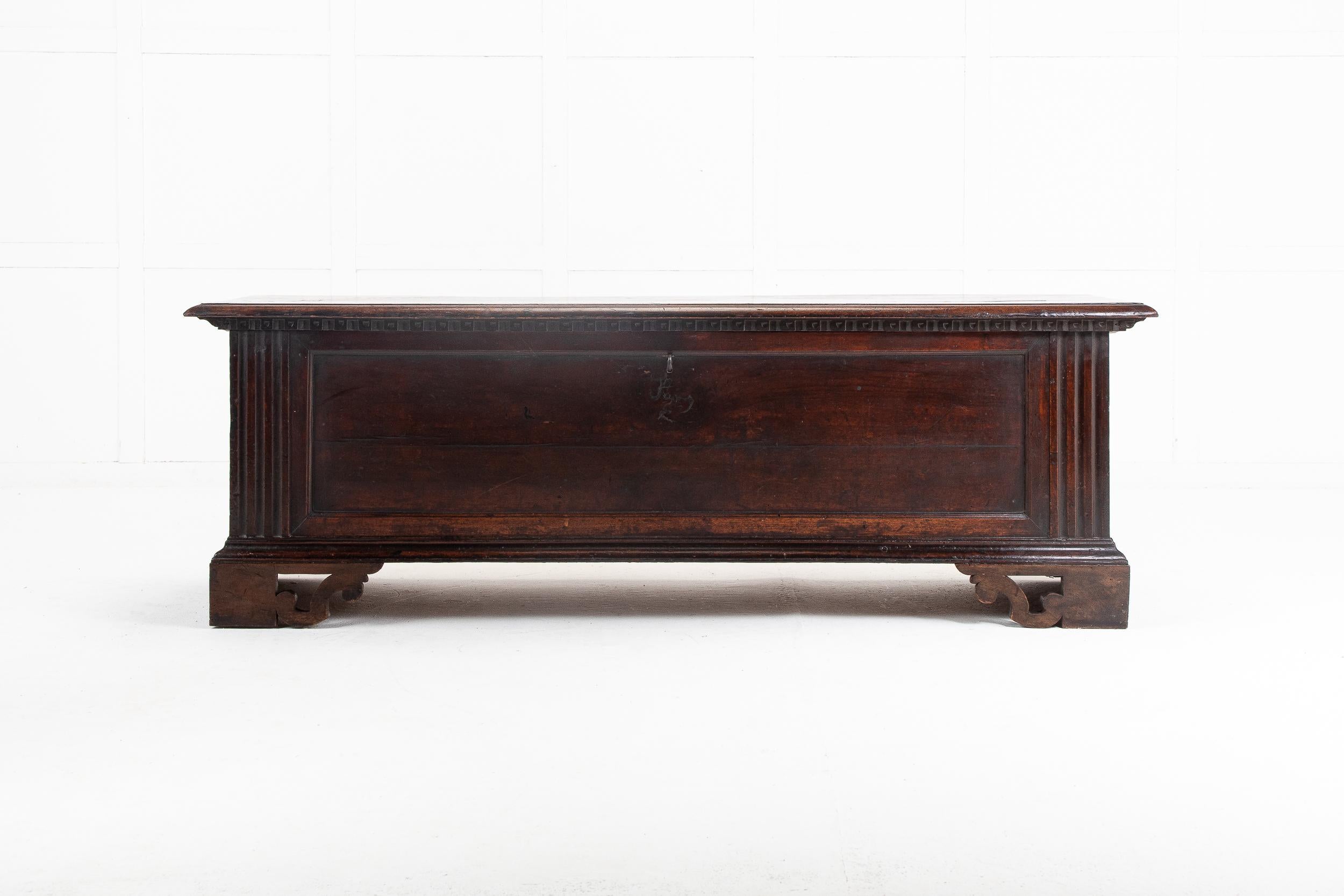 18th Century Italian walnut coffer of generous size. Having three planks for the top and carved moulding under the lid with iron hinges. Inside is lined with old paper. The front panel is plain and flanked by large grooved panels. Panelled sides and