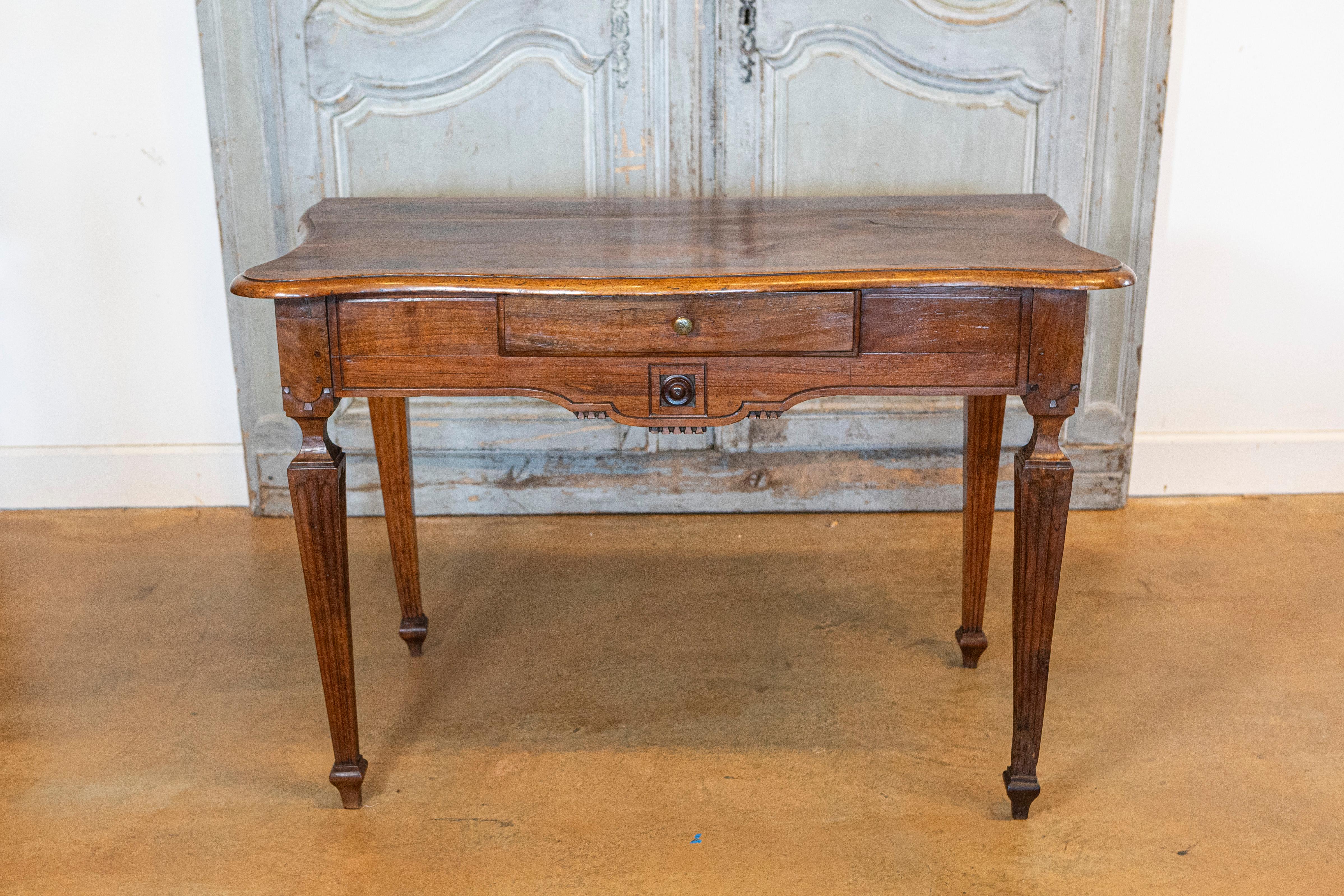 An Italian walnut console table from the 18th century with serpentine top, single drawer, carved apron and tapered legs. Emanate the grandeur of 18th-century Italian artistry with this sumptuous walnut console table. The eye is instantly drawn to