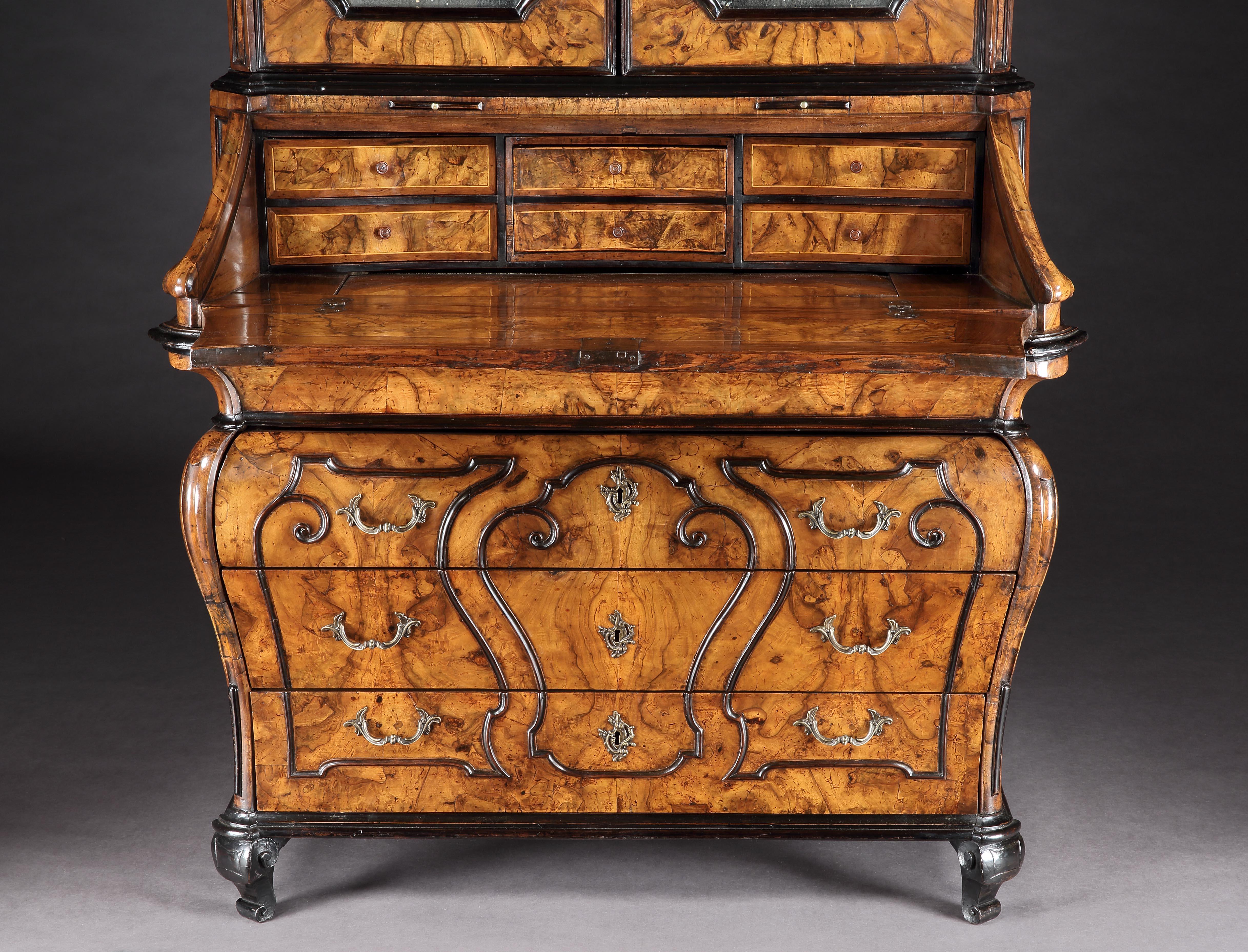 A good Lombardy Bureau cabinet of the 18th century
 
Constructed in a well patinated walnut; rising from scrolled feet, supporting a bombe form base with three inset shaped long drawers; the lockable drop front fall encloses two banks of three