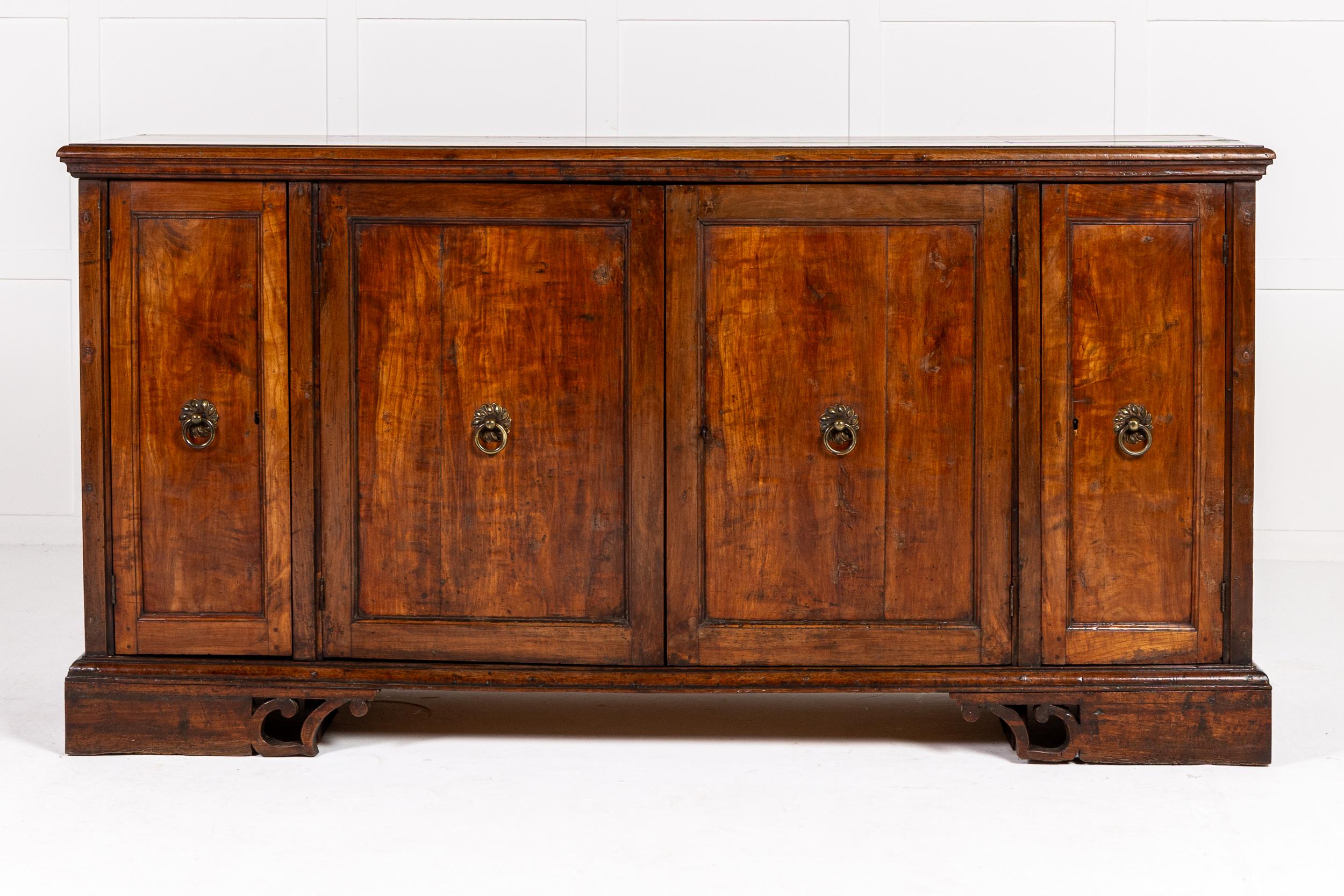 Un'interessante credenza/armadio in noce del XVIII secolo.

Questo mobile ha un semplice piano a listelli sporgenti sopra una serie di quattro ante a pannelli, due più larghe al centro e più strette alle estremità. Dietro le strette ante ci sono dei