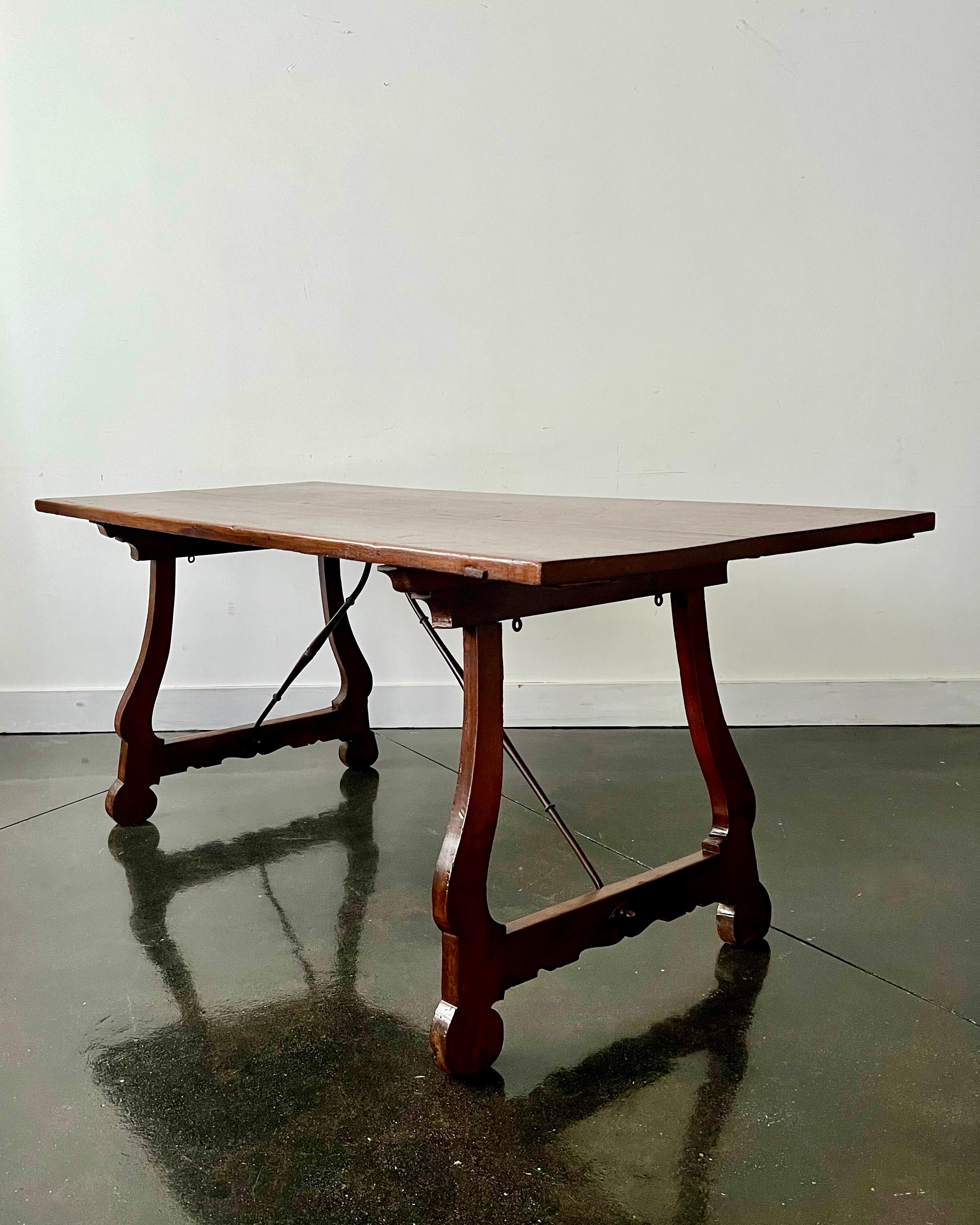 Italian 18th century walnut trestle table/console/center table with scrolled, carved supports joined by wrought iron stretcher and topped with solid walnut rectangular top.