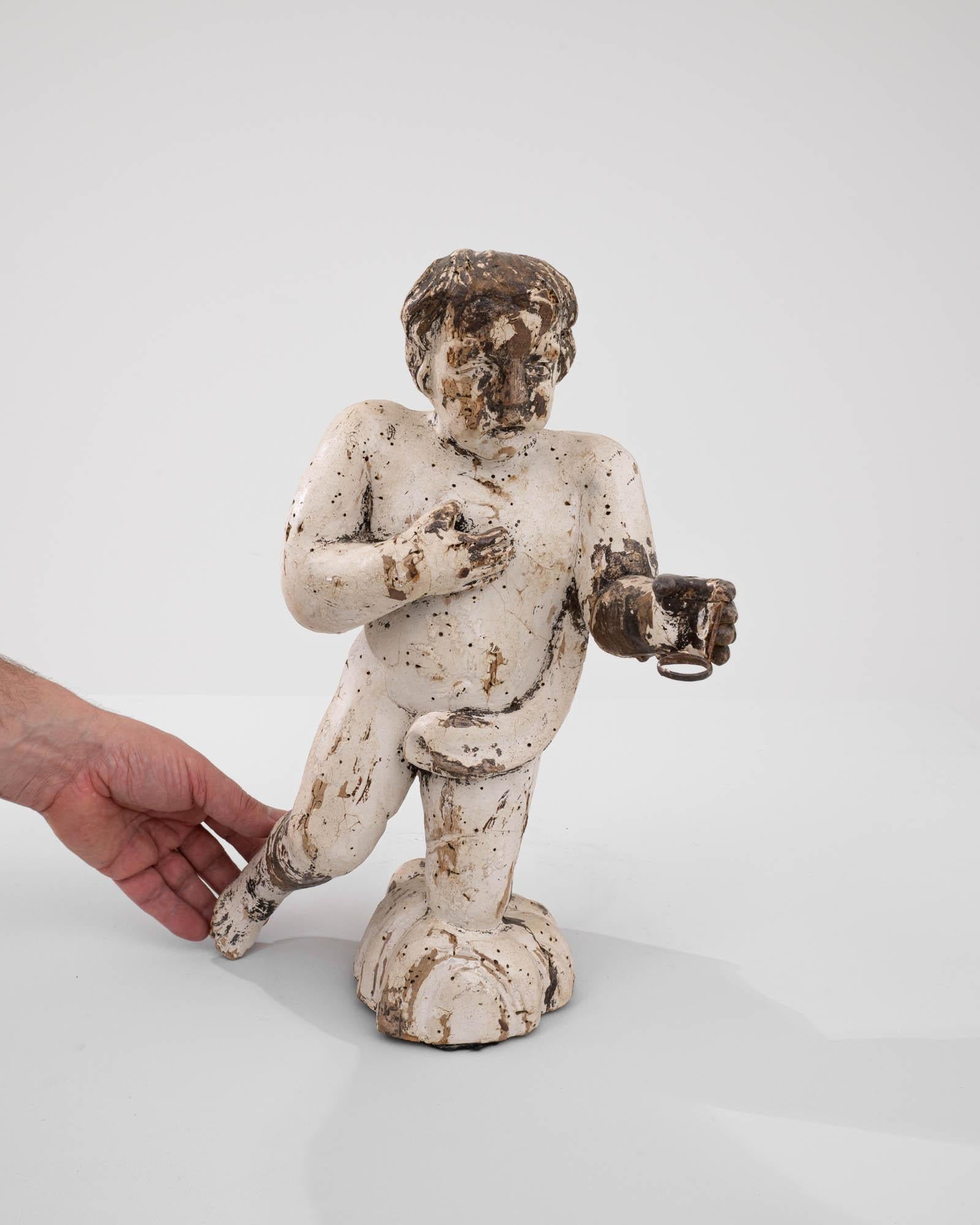 This 18th Century Italian Wooden Sculpture captivates with its rustic allure and storied past. Carved with a delicate yet masterful hand, it portrays the figure of a cherub, a timeless symbol of beauty and innocence. The sculpture's weathered