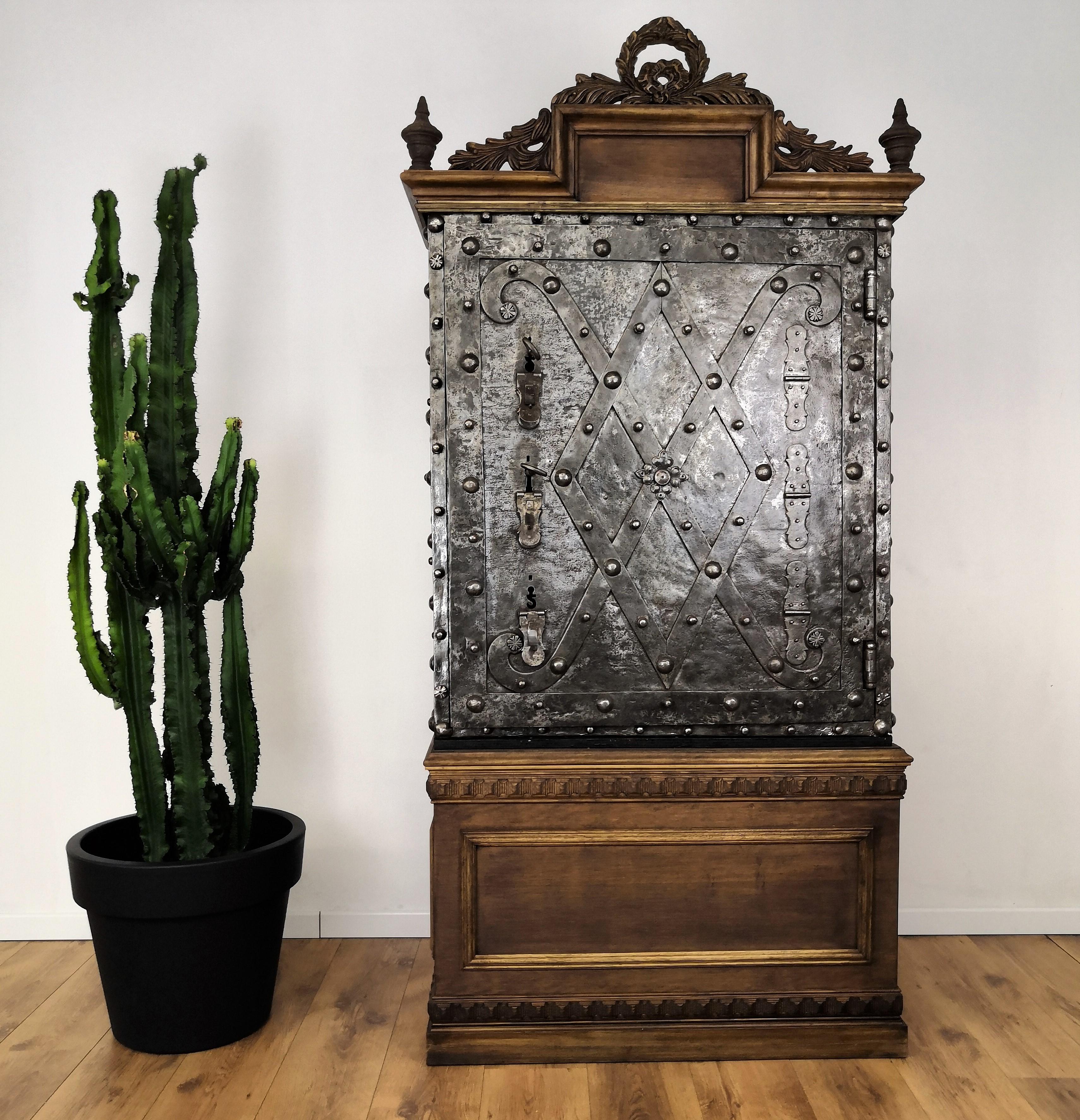 Late 18th century Northern Italian forged wrought iron antique safe with typical all-around external hobnails and beautiful decorations on the front door with its wooden base and top.
The opening mechanism works with two authentic and amazingly