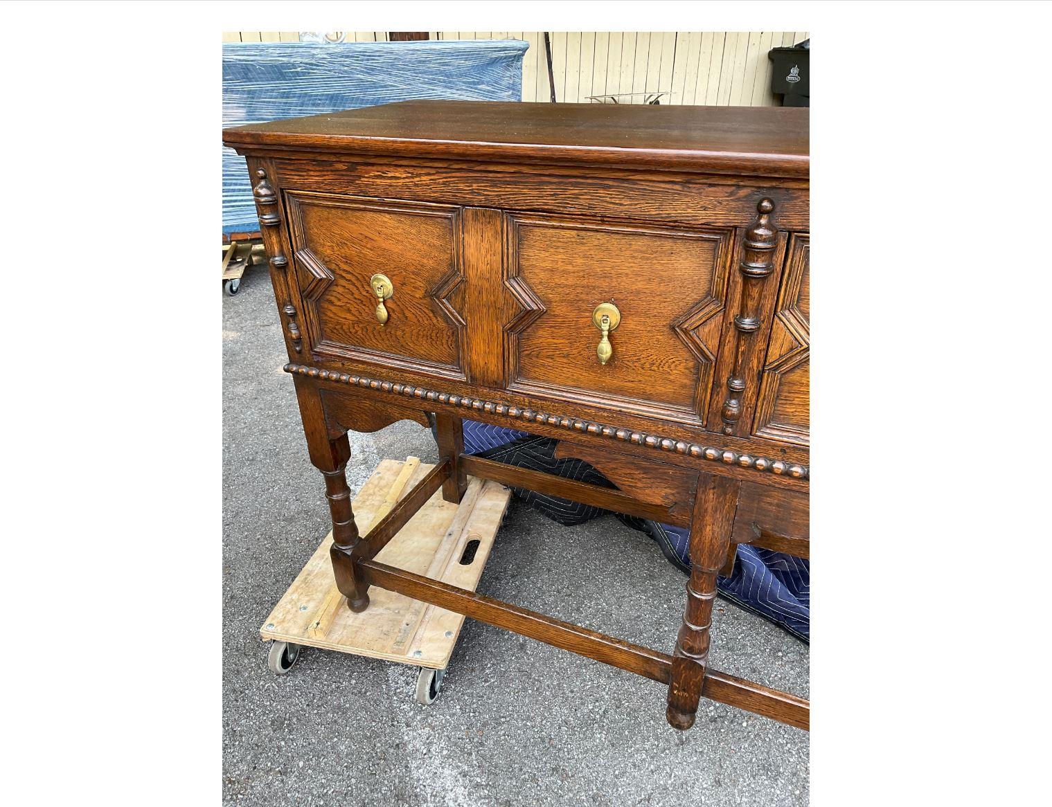 This amazing English server has such an aura of old-world charm about it. It is from the Jacobean period, dating to the 1800s, and has an excellent patina. The server has beautifully done geometric drawer fronts with original pulls, and a wooden