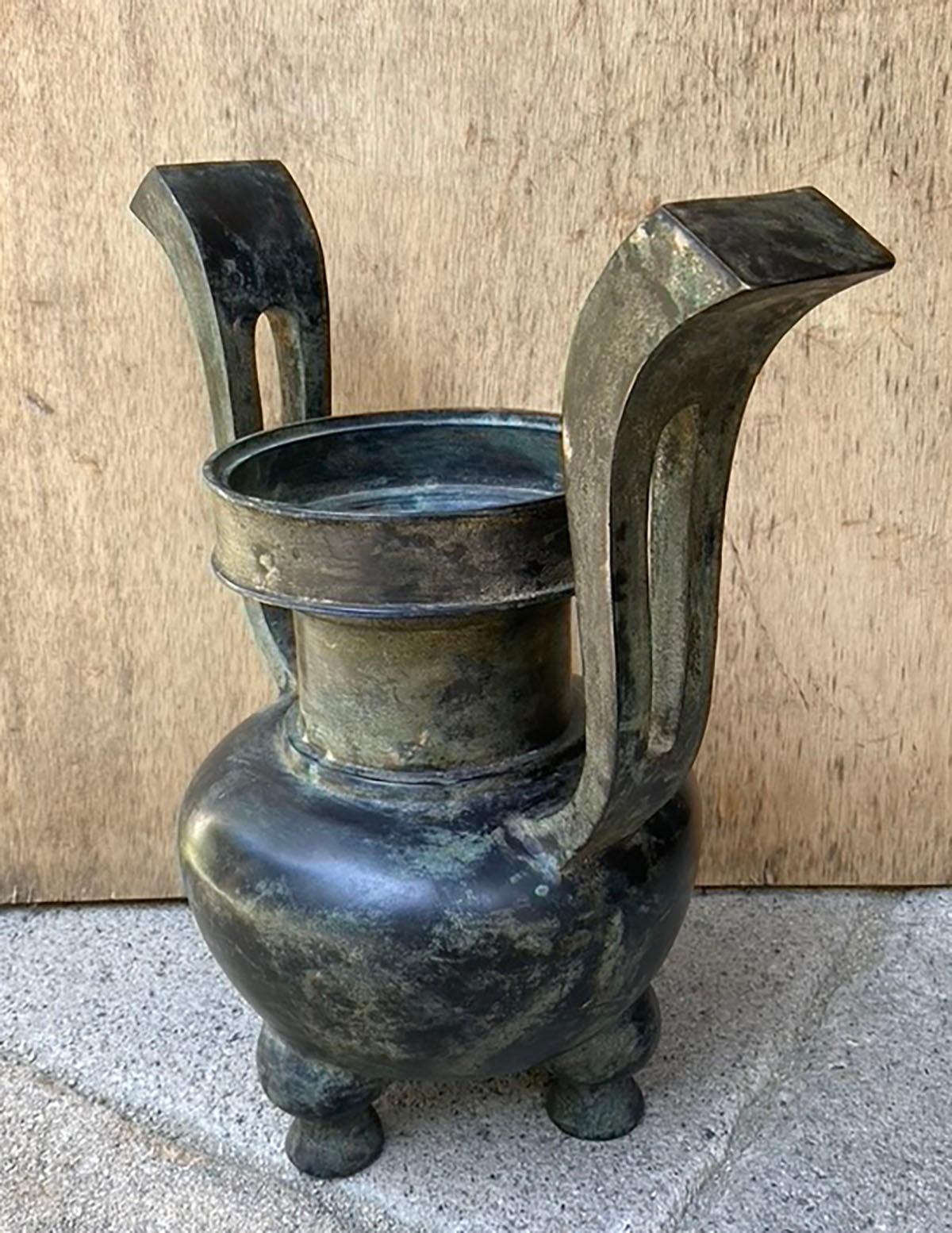 Un elegante vaso da tempio giapponese del XVIII secolo in bronzo con una caratteristica base a tre gambe e due manici graziosamente arcuati. La superficie mostra una splendida patina invecchiata, testimonianza di secoli di uso rituale e di serenità