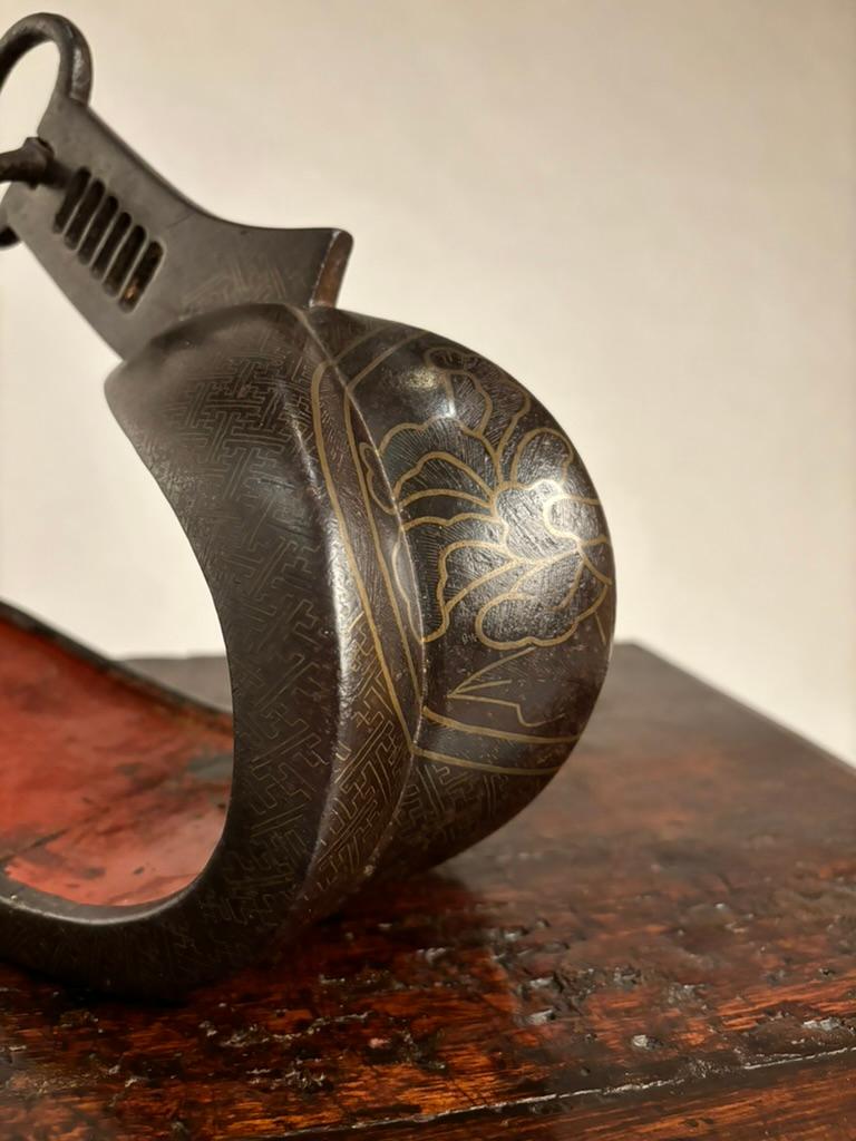 18th century iron abumi of typical form, the stirrup inlaid in silver, an encircled peony flower crest surrounded with a geometric pattern, the interior retains the original wood lining decorated in red lacquer. The sides and underside also inlaid.