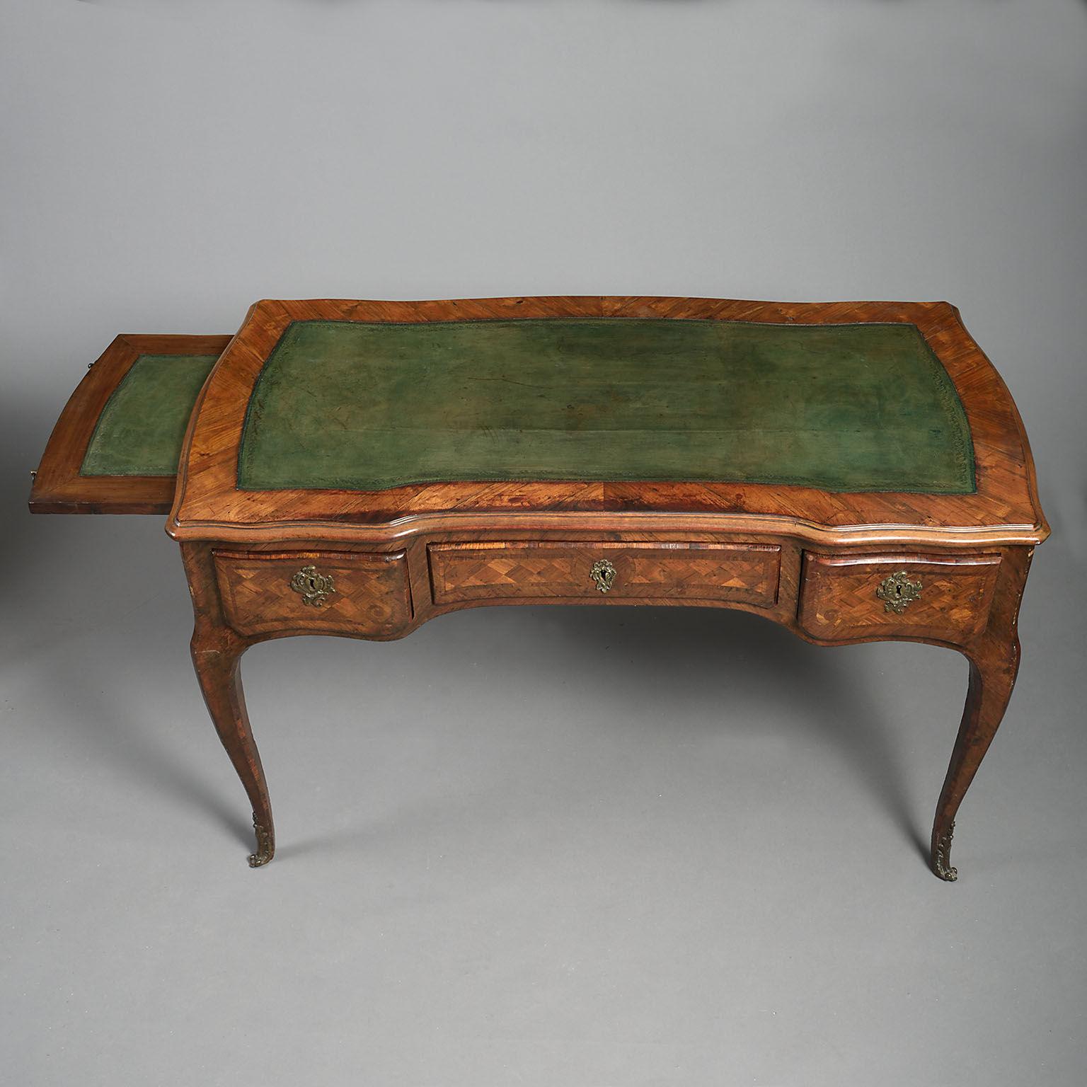 The shaped, moulded rectangular top inset with a green tooled leather writing surface above a long frieze drawer, flanked by two short shaped drawers and with slides to each end inset with green tooled leather on cabriole legs and gilt metal sabots.