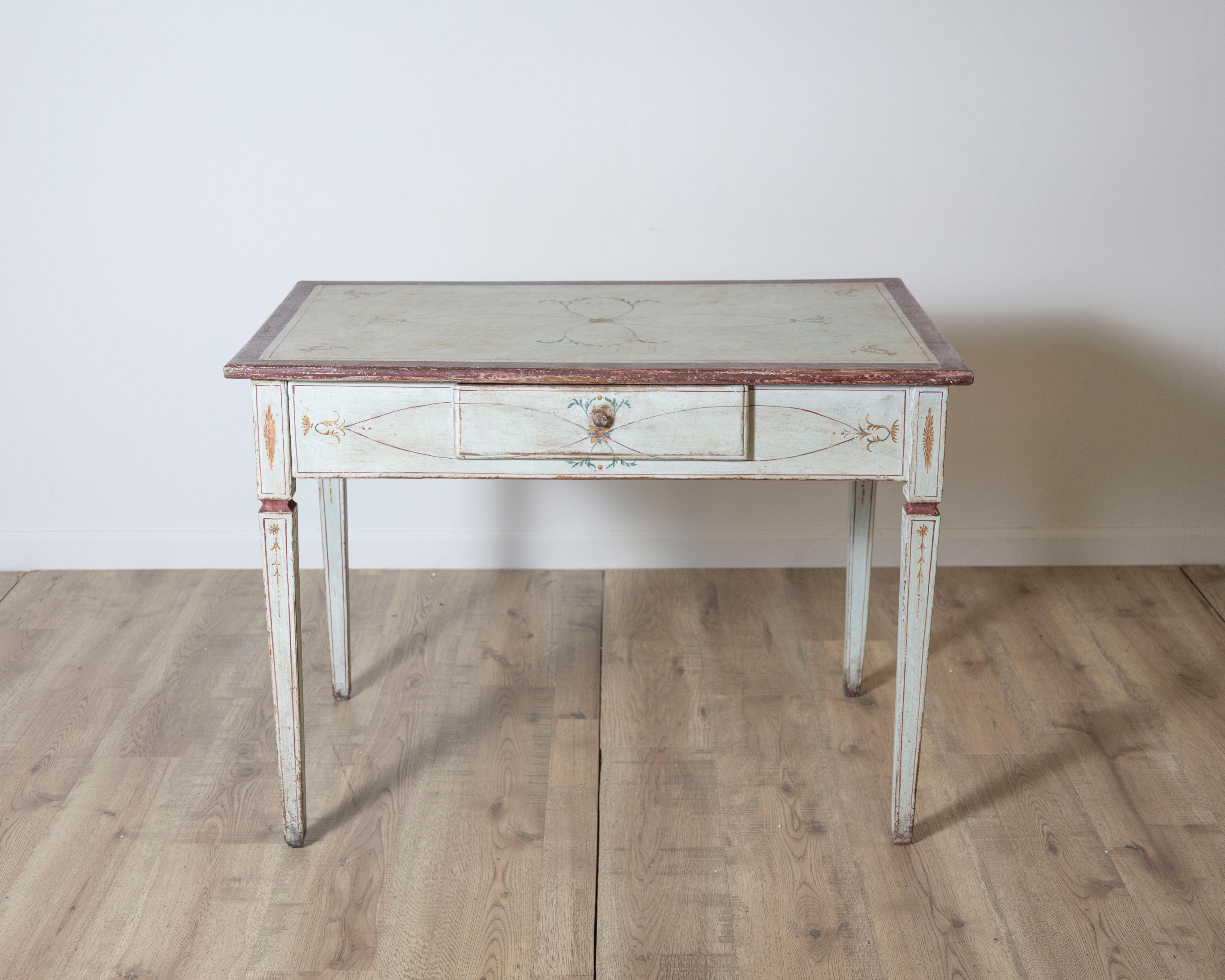 An elegant lacquered wooden desk table from Tuscany, dating to the Louis XVI period, late 18th century. This refined piece features delicate hand-painted neoclassical decorations in warm, muted tones over a pale ivory ground, reflecting the graceful