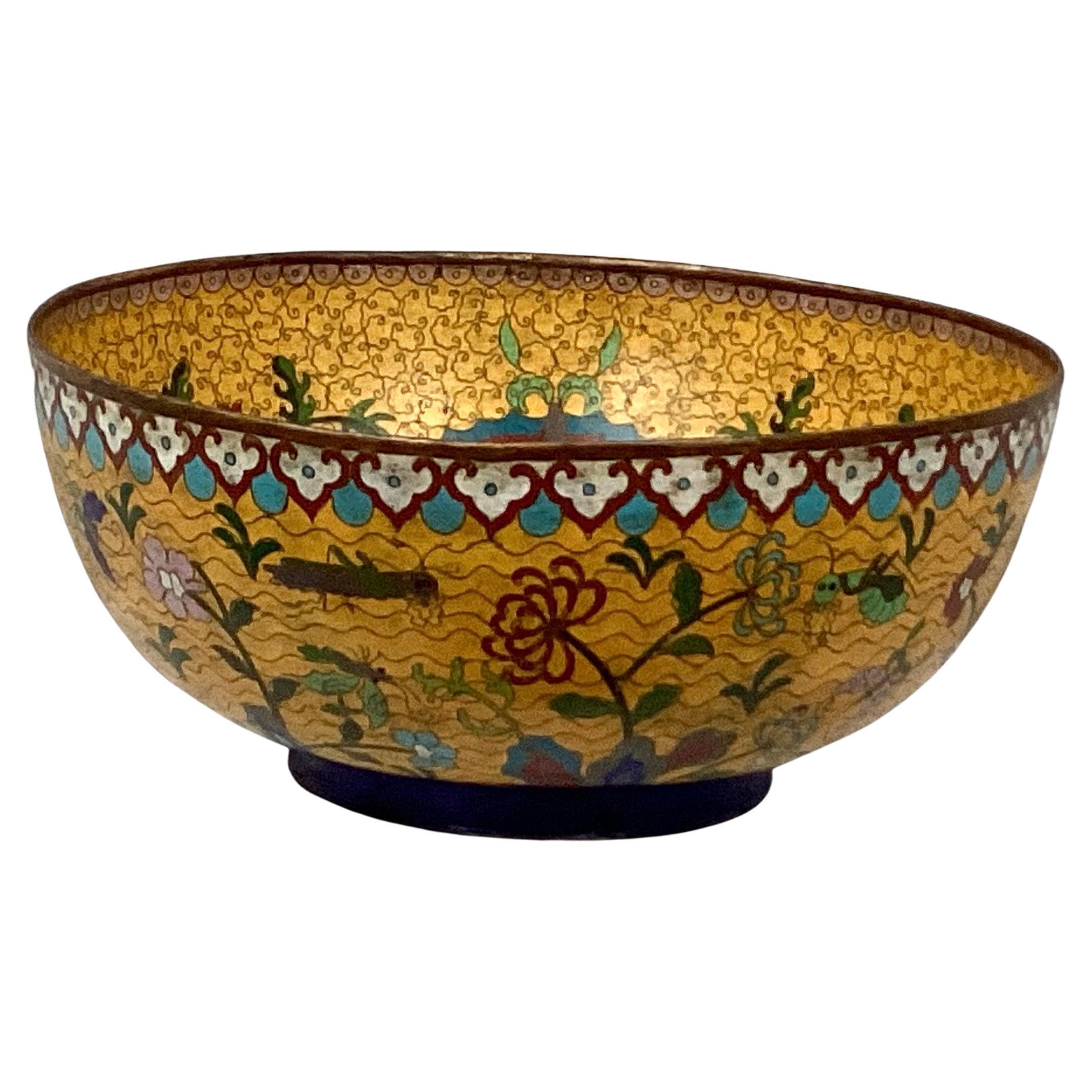 Rare 18th century Chinese Bronze Cloisonne enamel footed hand-painted bowl. Decorated with flowers and butterflies in colors of red, blue, and green on a mustard yellow background.