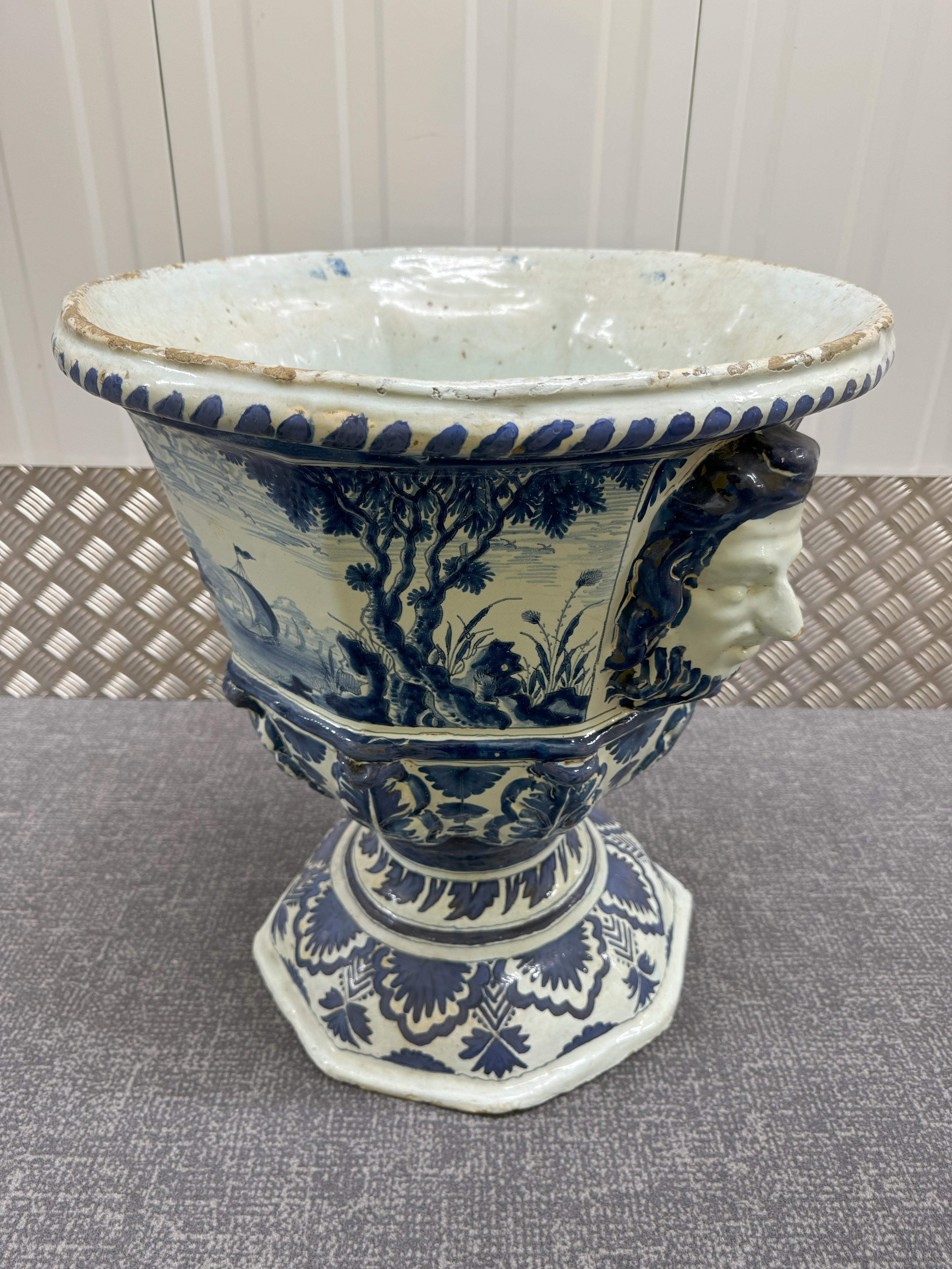 18th Century Large Delft Garden Urn, of octagonal form with mask handles 
painted in blue with river landscapes within foliate and leaf borders.  A good 
example of a Dutch Delft piece made in the 18th century with attractive hand painted