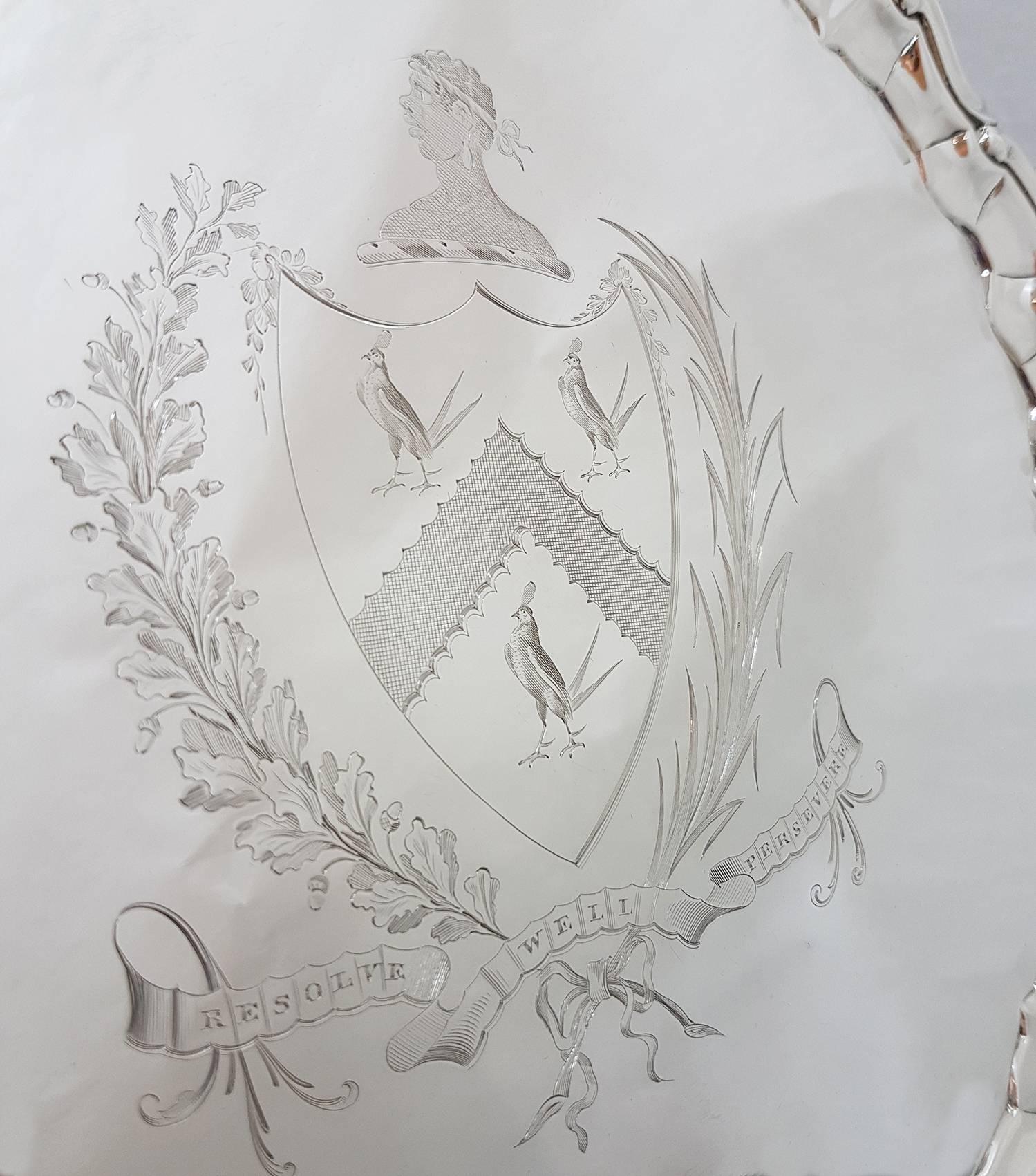 This fine antique George II sterling silver salver has a plain circular shaped form.

The surface of the salver is ornamented with a fine and impressive contemporary bright cut engraved coat of arms depicting a moor with the motto 
