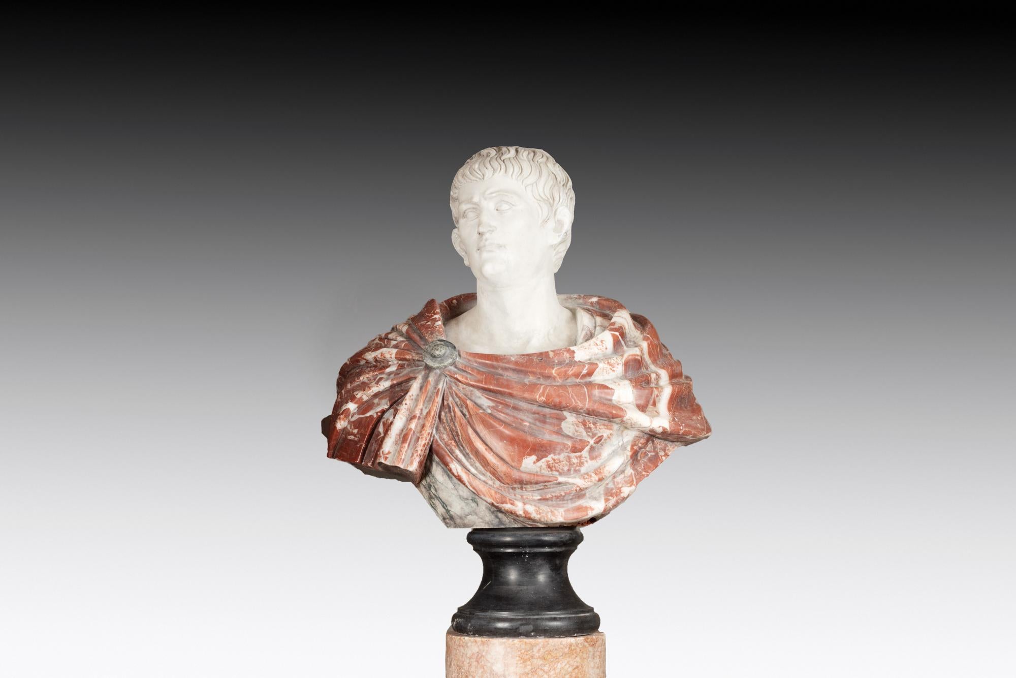 18th Century Italian Marble Bust of Caesar Augustus. His draped robe is hand-carved in red rosso levanto marble with the face modelled in contrasting white Carrara marble. The piece sits on a cylindrical plinth base of dark nero marquina.