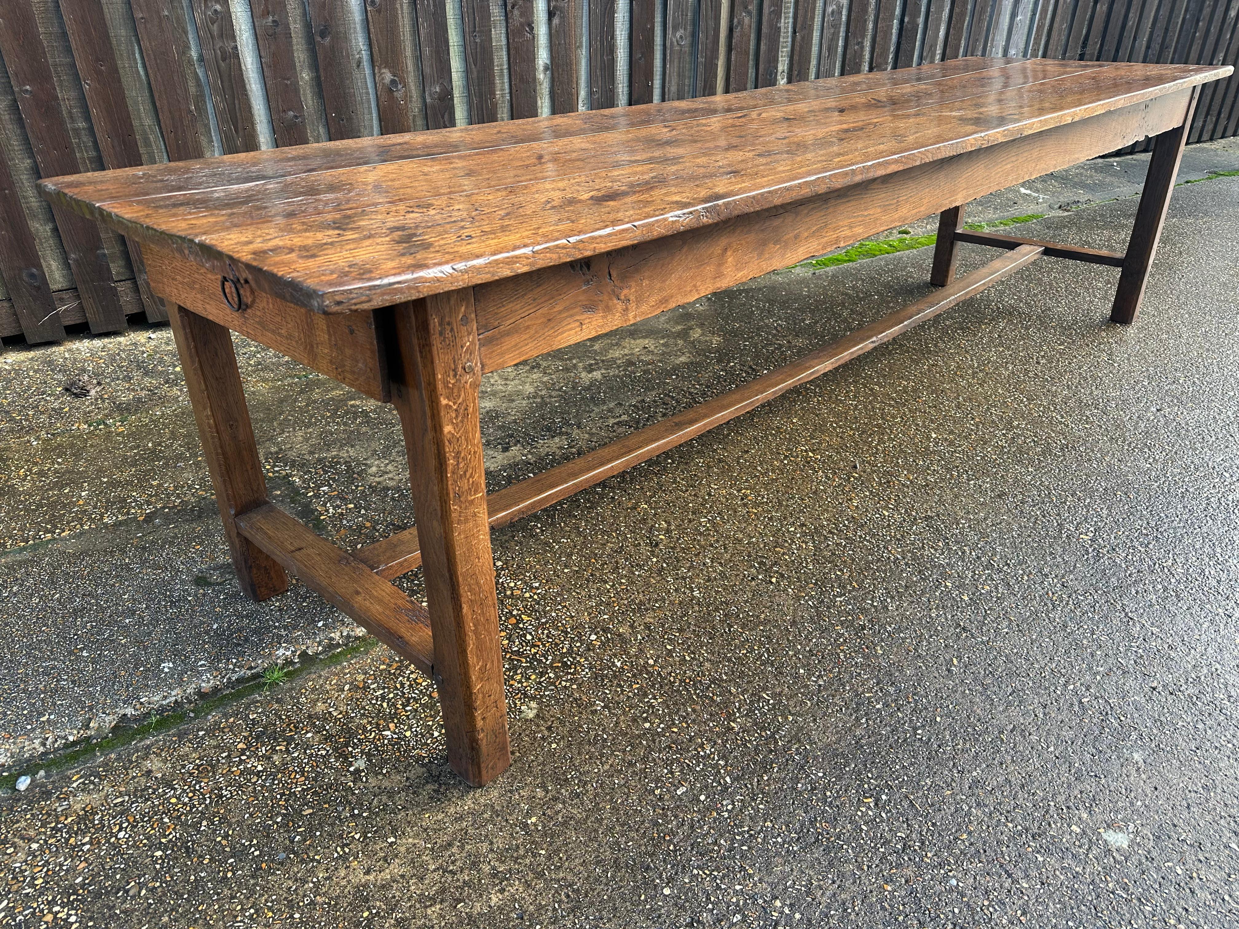 8th Century large oak farmhouse dining table with one drawer on the end. This 18th century large farmhouse dining table is a remarkable antique piece with exquisite craftsmanship. It features a three plank top, showcasing the natural beauty of the