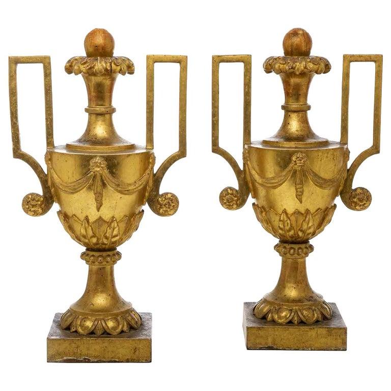 Ensemble de deux grands vases néoclassiques en bois doré du XVIIIe siècleune paire de vases centraux à poignée en bois sculpté et doré, sur base carrée, portapalme réalisé en bois de pin de Cembran sculpté avec des motifs feuillus néoclassiques