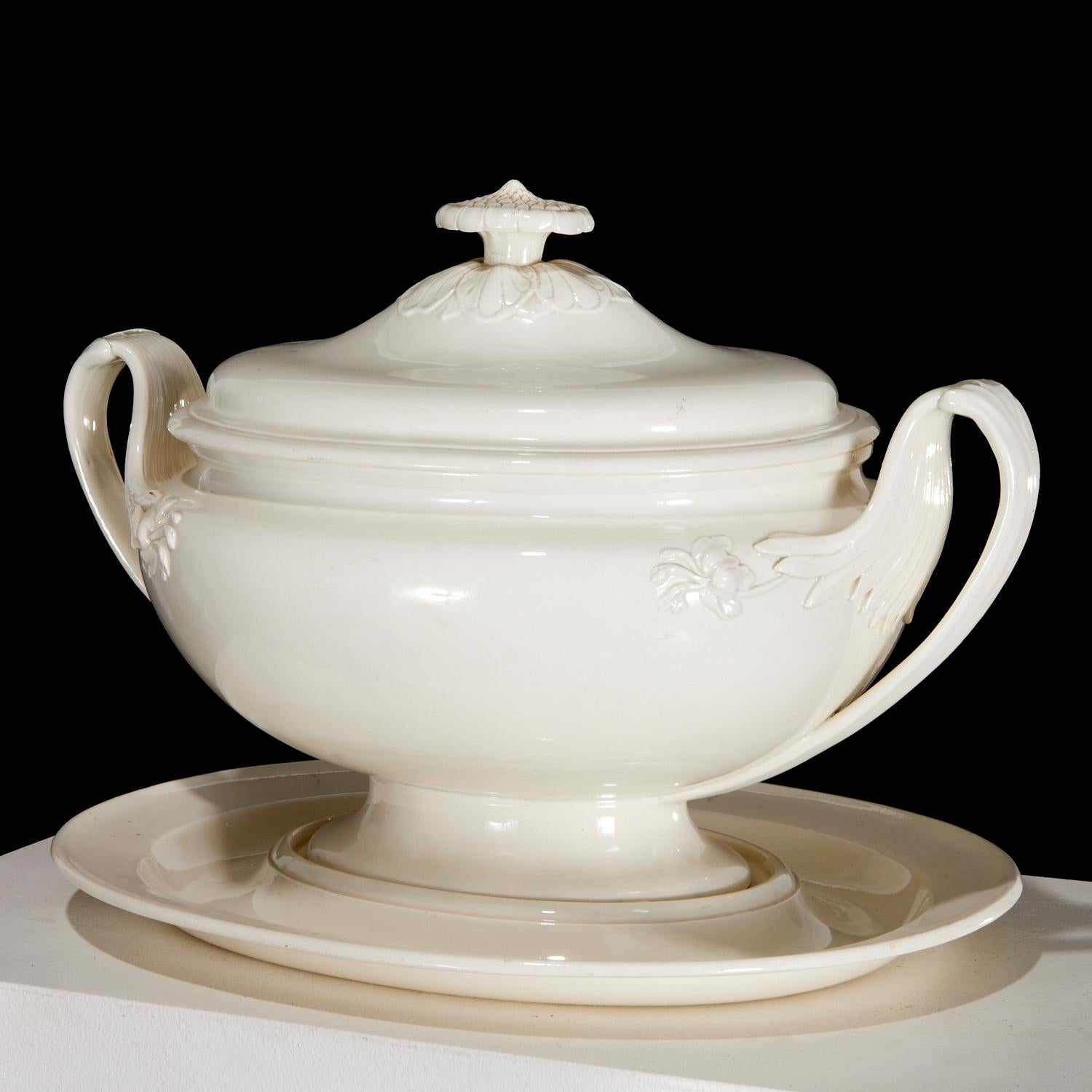 English Large Creamware Tureen, Cover & Stand,
Wedgwood,
Circa 1790-1800

The large creamware soup tureen, cover and stand is of an oval form with dramatic handles with large molded leaf terminals with a molded flower head on the side of the tureen
