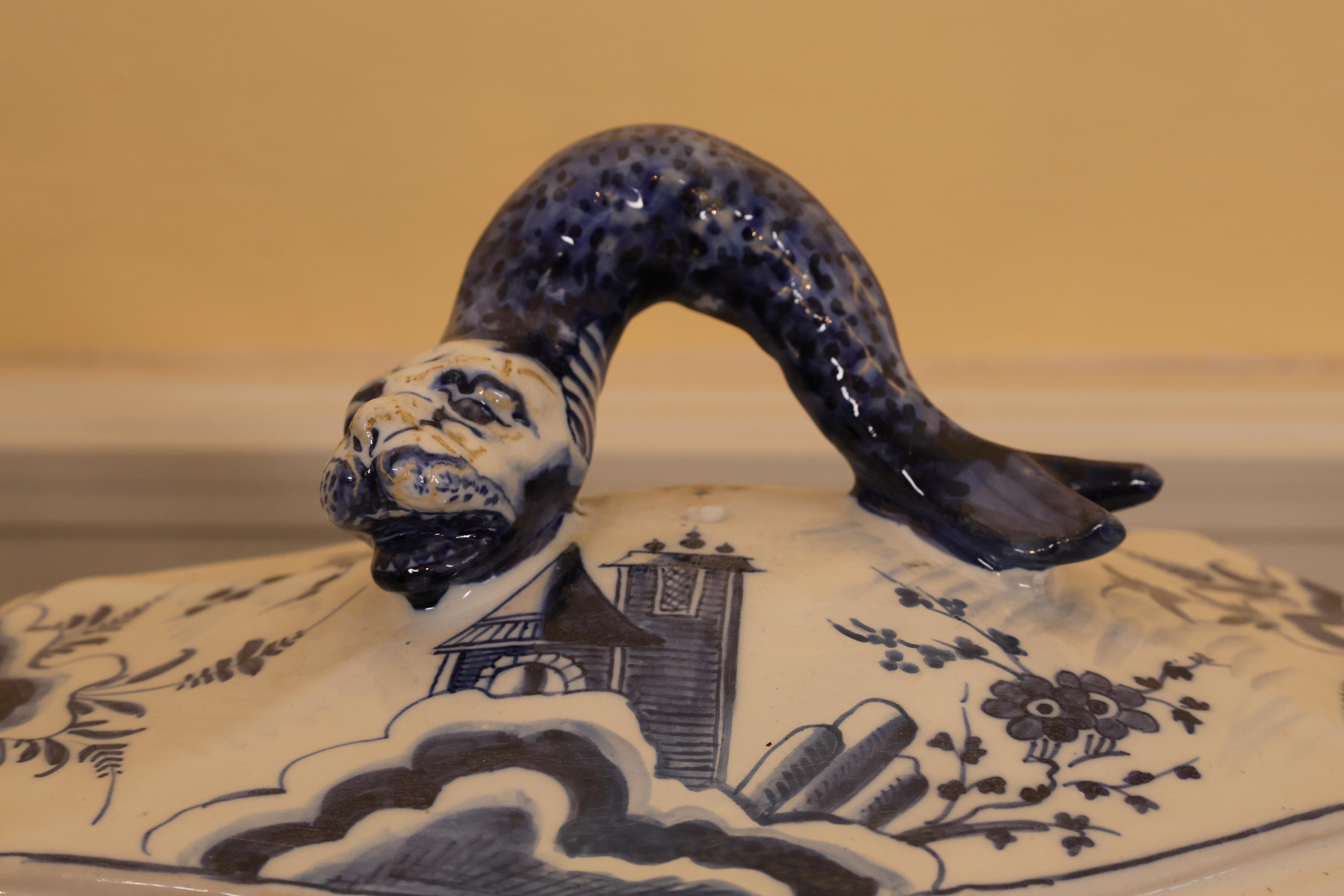 Una grande zuppiera di maiolica in vibrante blu cobalto, in stile tardo barocco, realizzata da Rörstrand nel 1747. Presenta piccole riparazioni e ritocchi. Il coperchio è sormontato da un terminale a delfino. La decorazione comprende mascheroni,