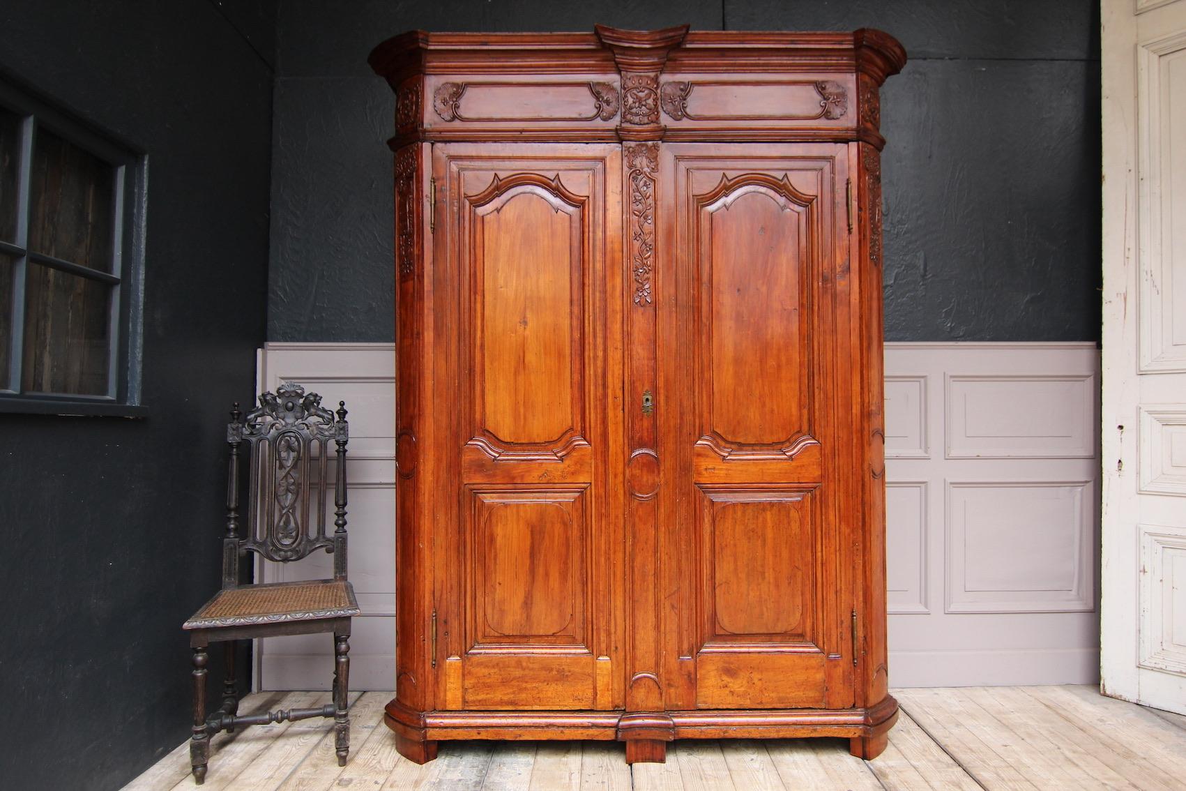 Original 18th century Liège wardrobe. Rare version in cherry wood.

Dismountable corpus with sloping rounded pilasters and heavy cornice with cranked profile. Two doors hung on external brass fittings. Both doors and sides of the corpus
