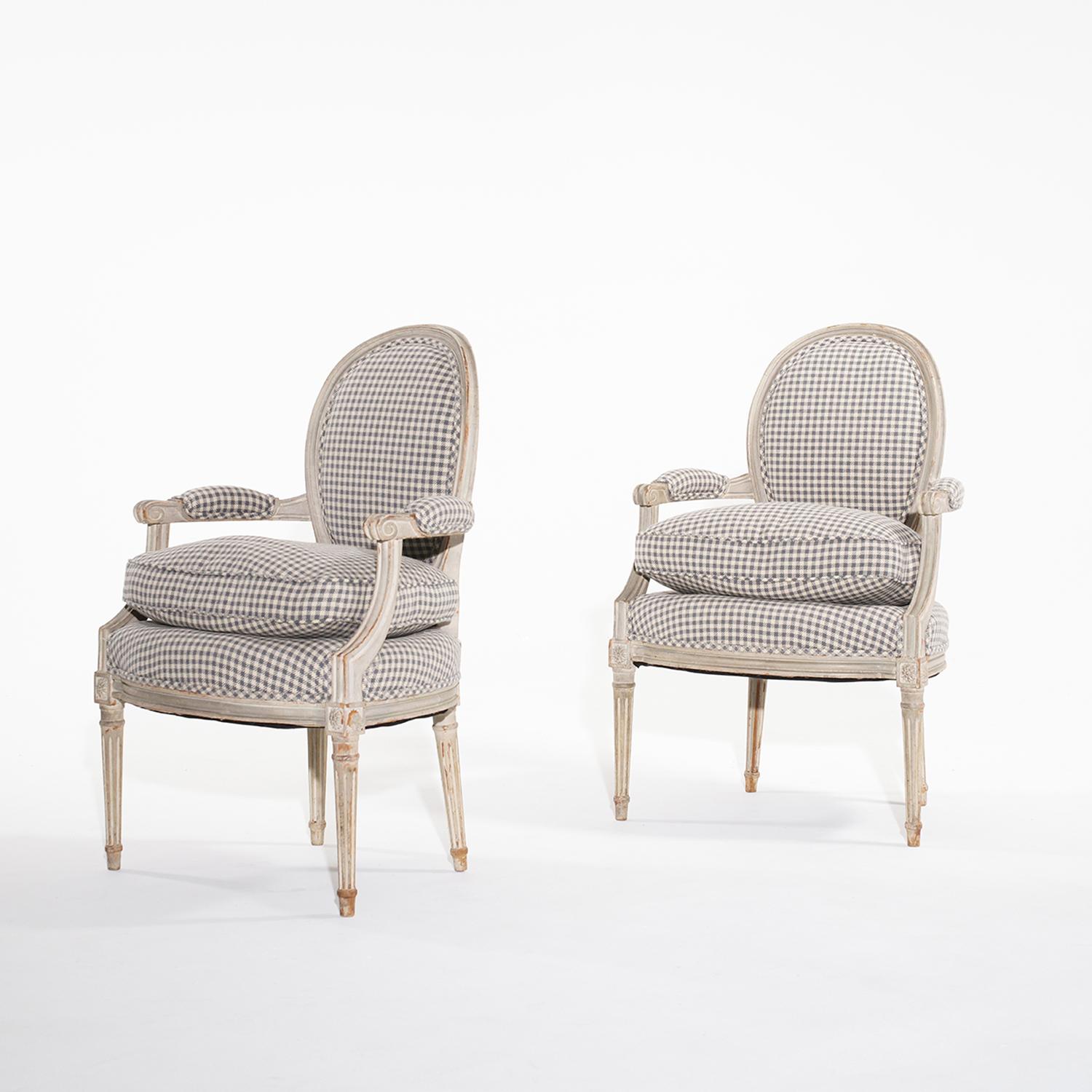 A light-grey, antique Swedish Gustavian pair of armchairs with a loose seat cushion, made of hand crafted painted Pinewood in good condition. The curved shield back of the Scandinavian club chairs have an oval padded backrest particularized by a